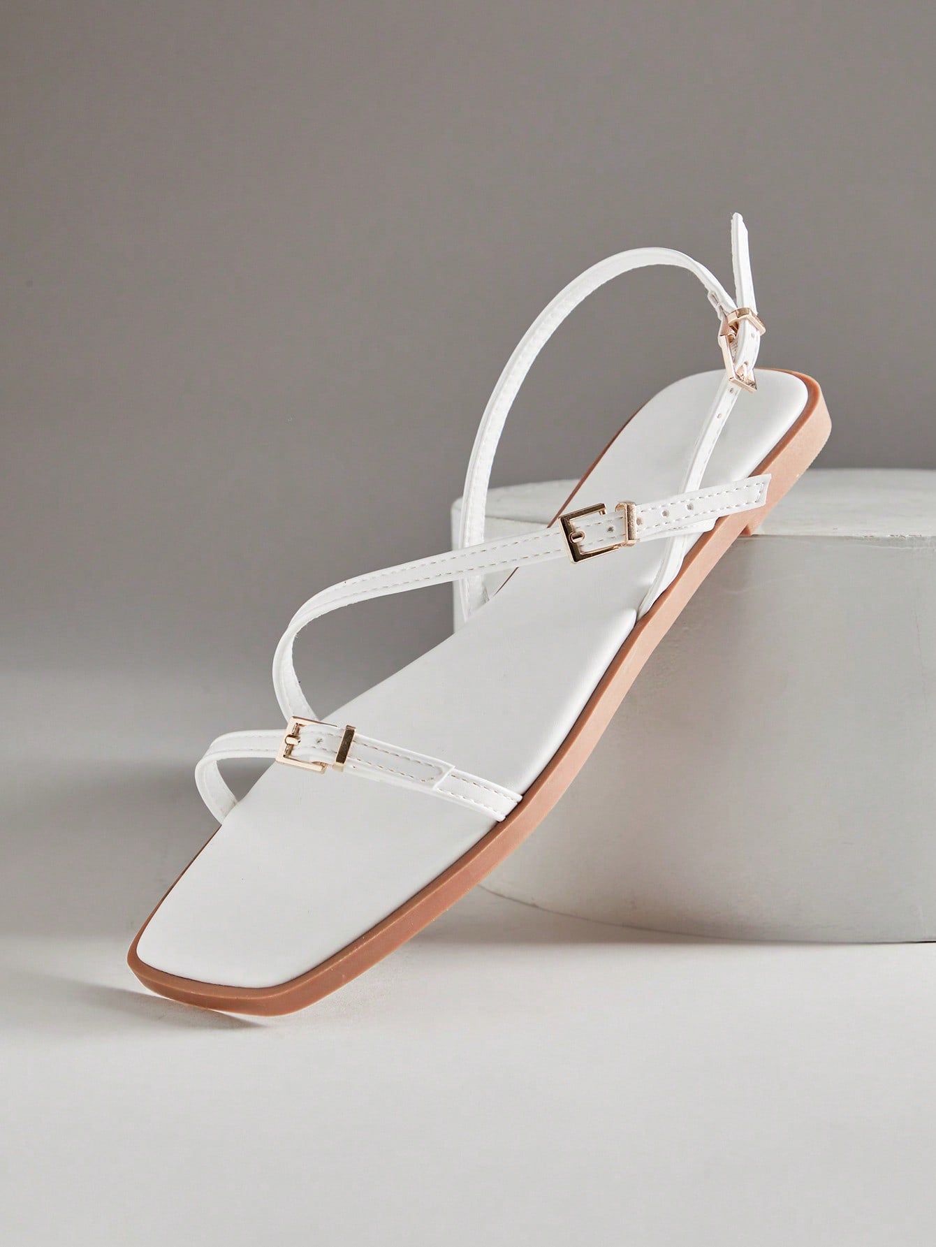 Women's flat open-toe sandals featuring a buckle detail and PU leather construction with a flat sole.