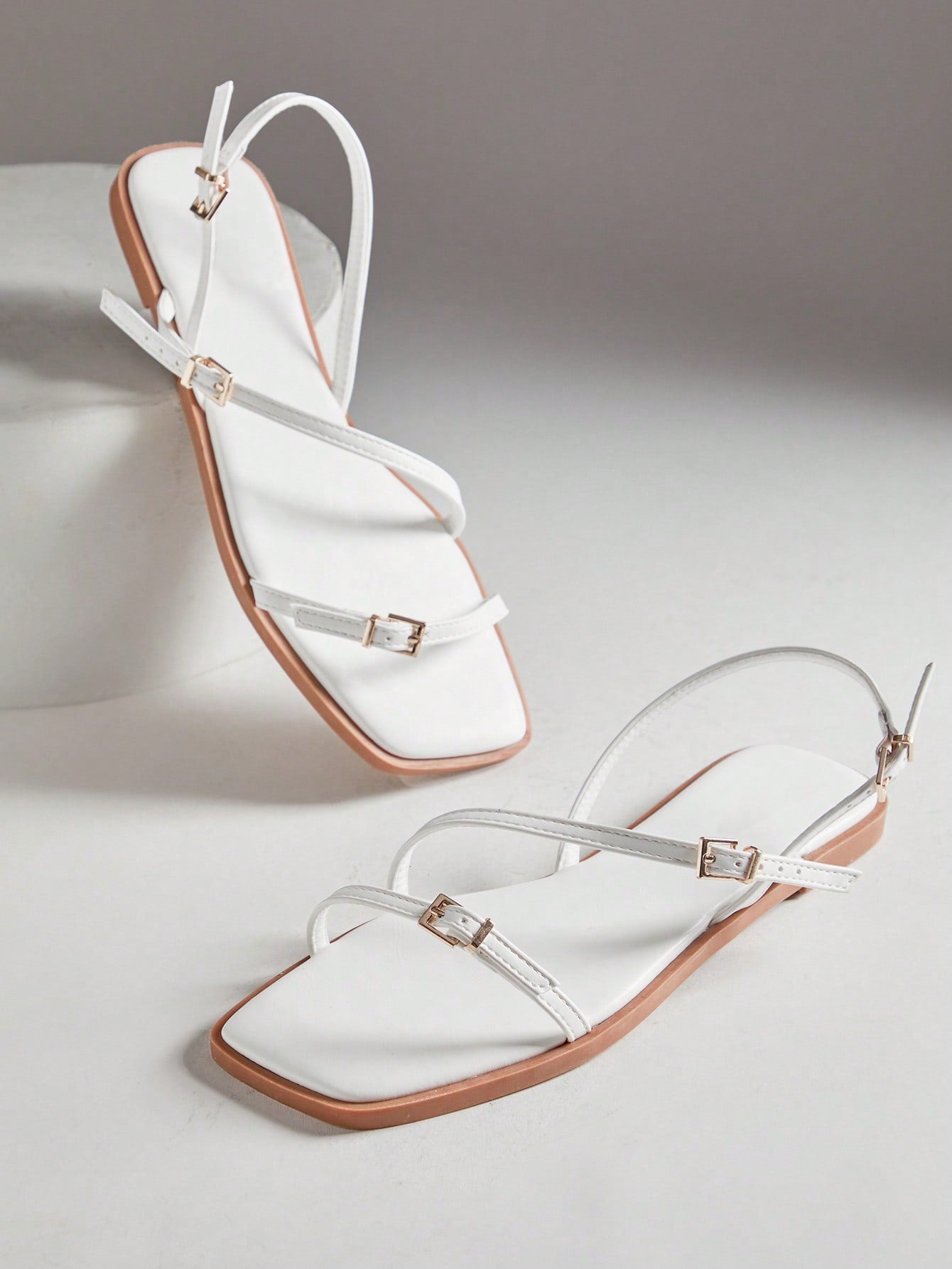 Women's flat open-toe sandals featuring a buckle detail and PU leather construction with a flat sole.