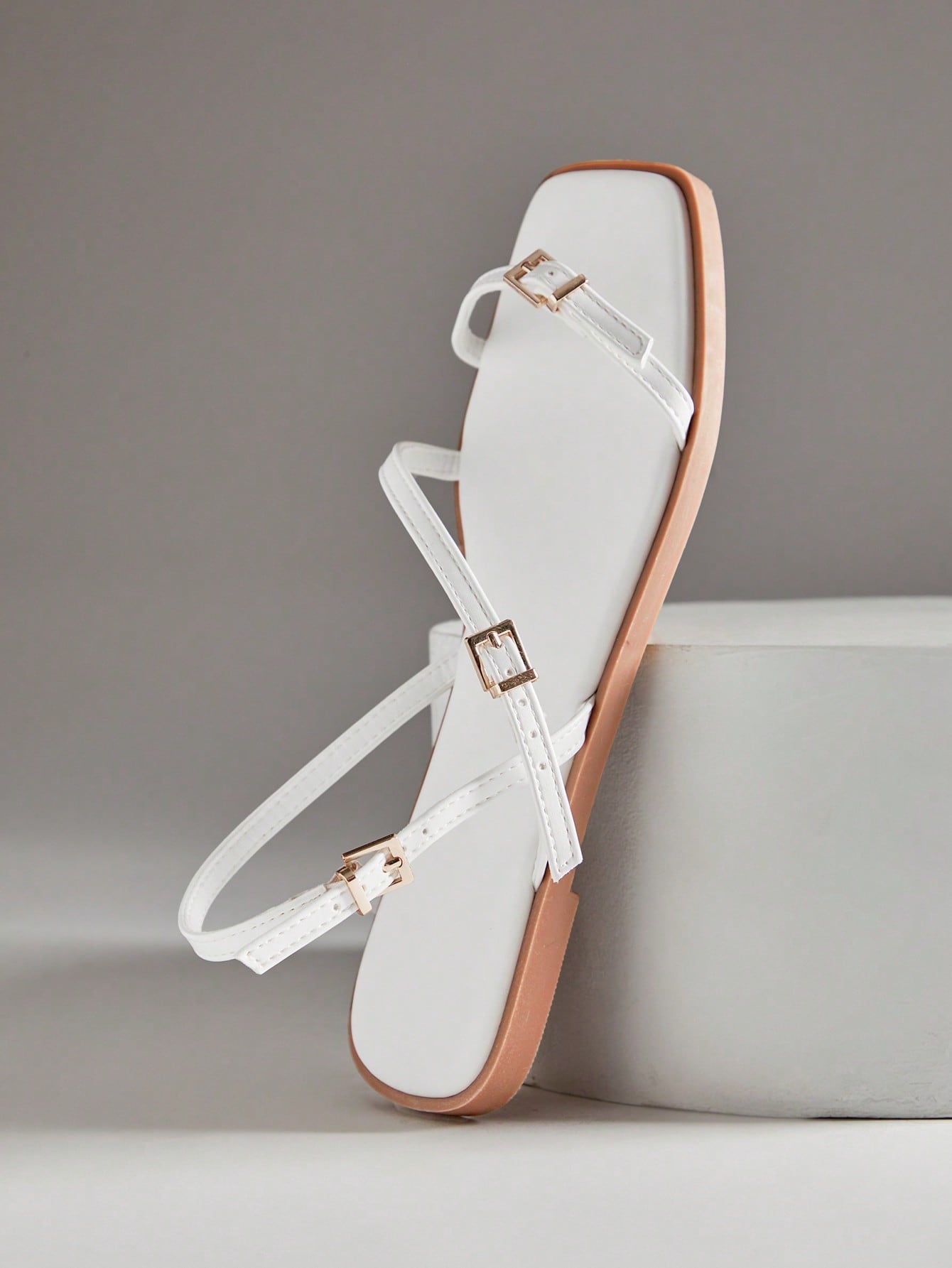 Women's flat open-toe sandals featuring a buckle detail and PU leather construction with a flat sole.