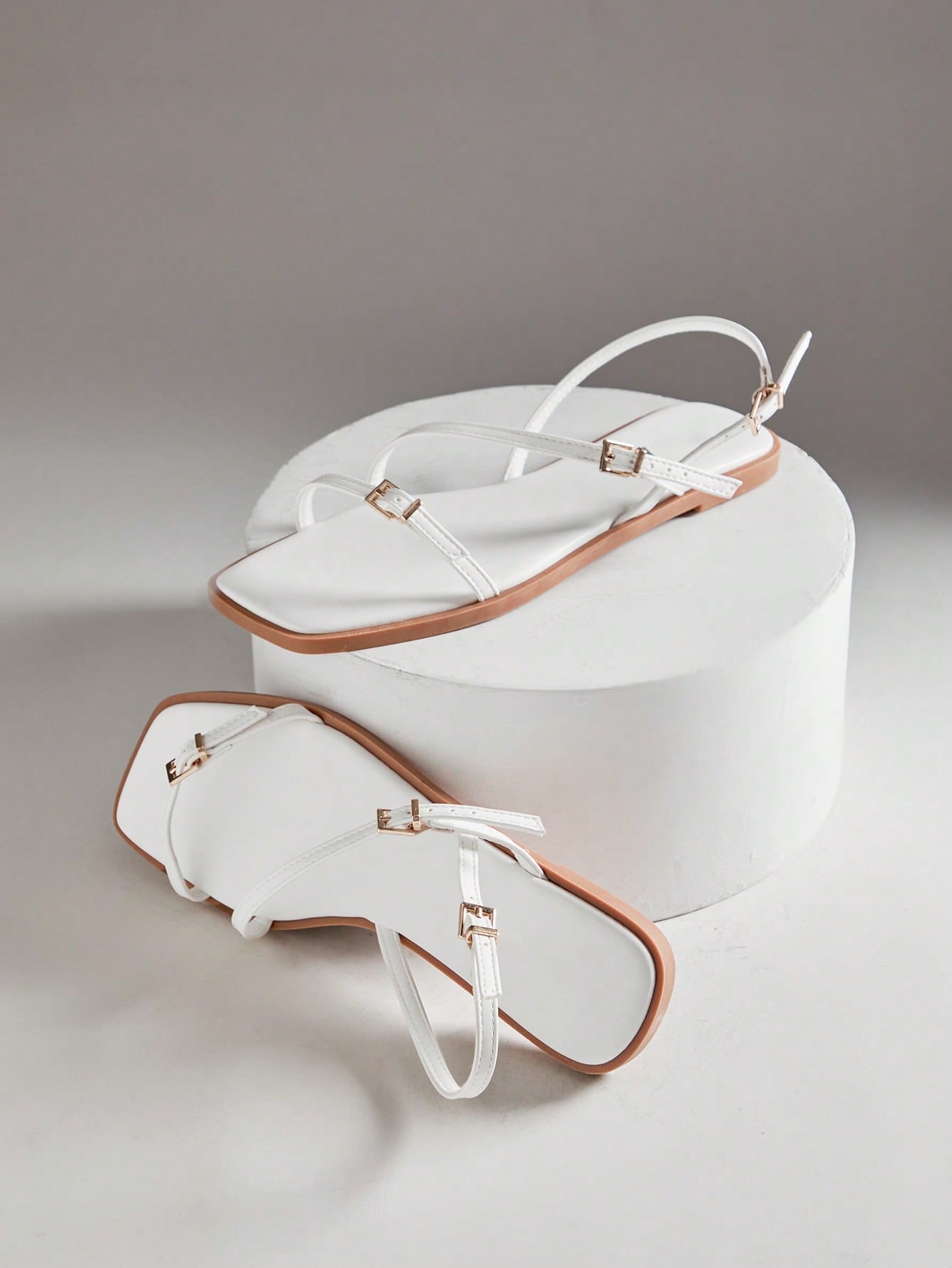 Women's flat open-toe sandals featuring a buckle detail and PU leather construction with a flat sole.
