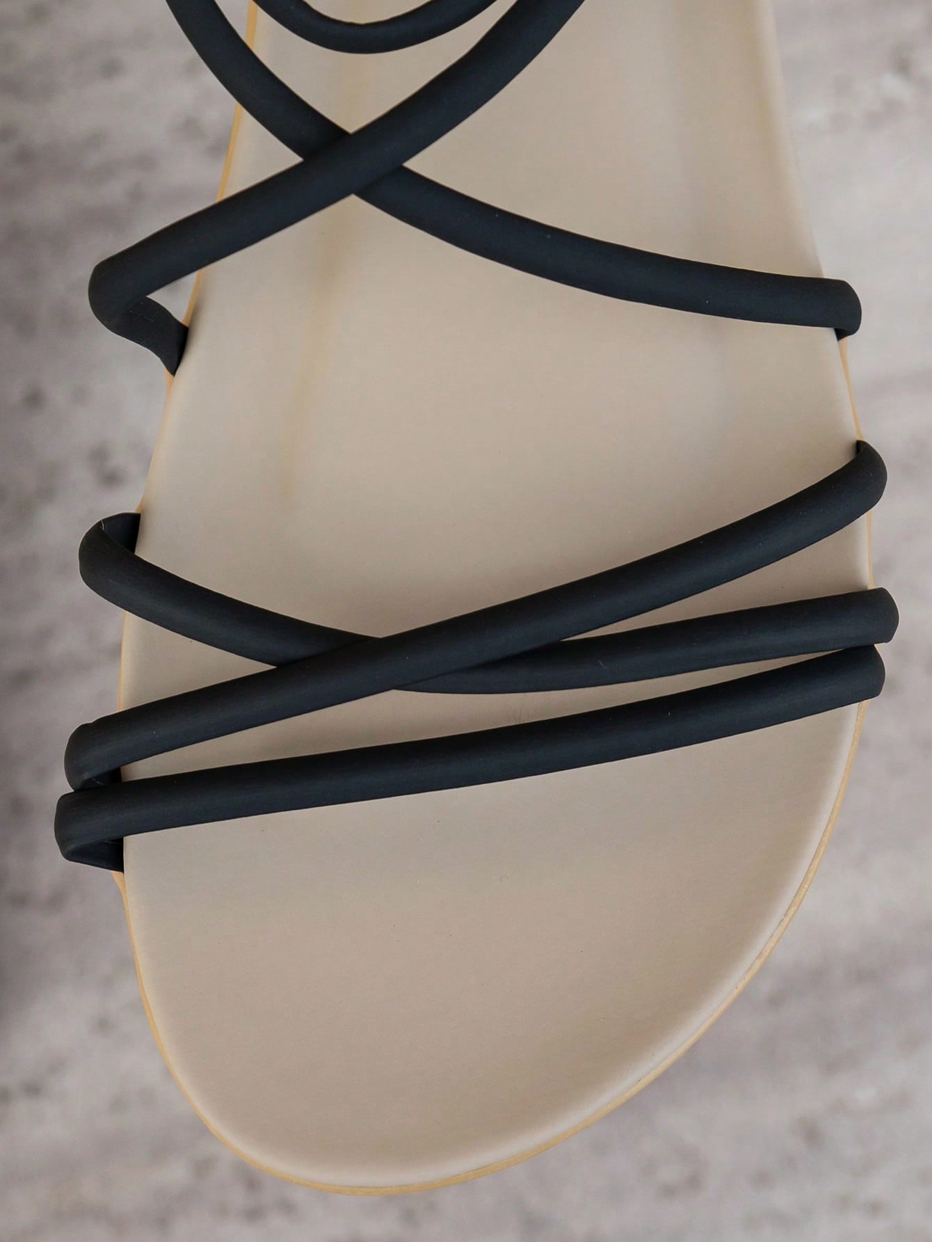 Black women's flat sandals with a striped criss cross upper, open toe, and ankle strap style for beach and vacation wear.