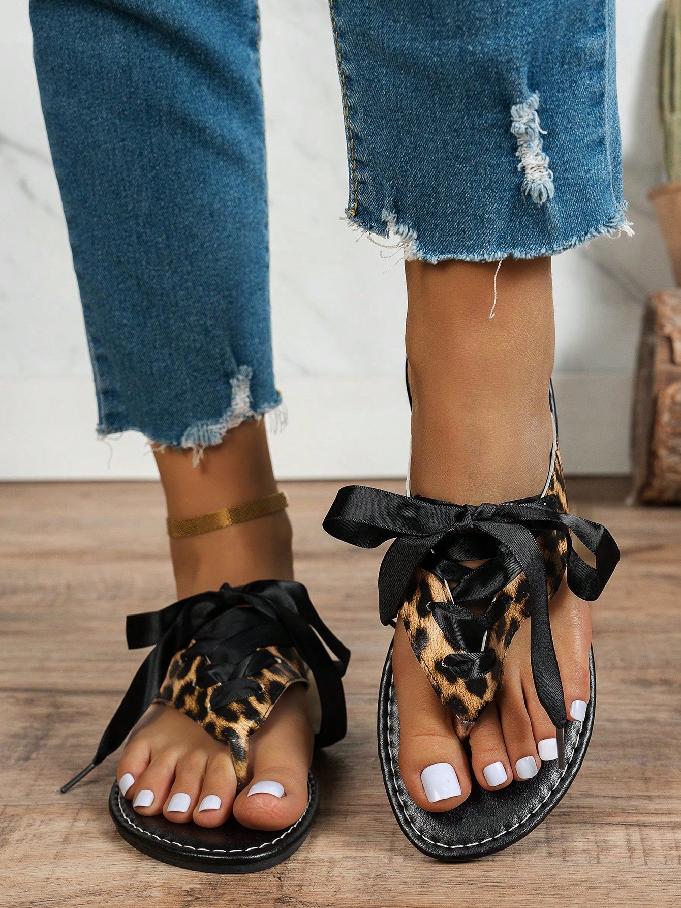 Women’s black flat toe post sandals with a leopard print satin ribbon bow, suitable for vacation, outdoor use, and everyday wear.