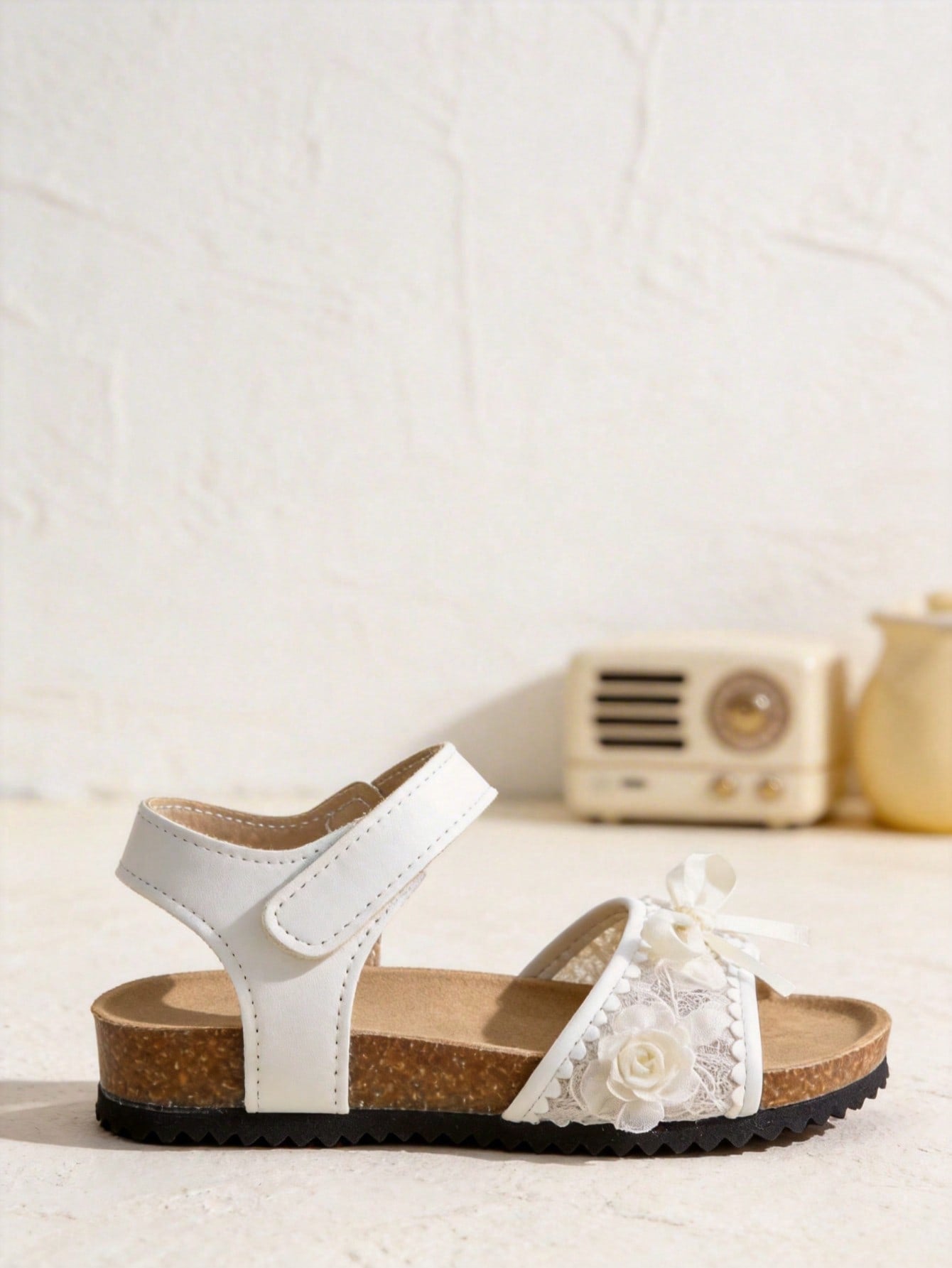 Pair of girls' pink open-toe flat sandals with ankle straps, buckle details, and a non-slip black rubber outsole.