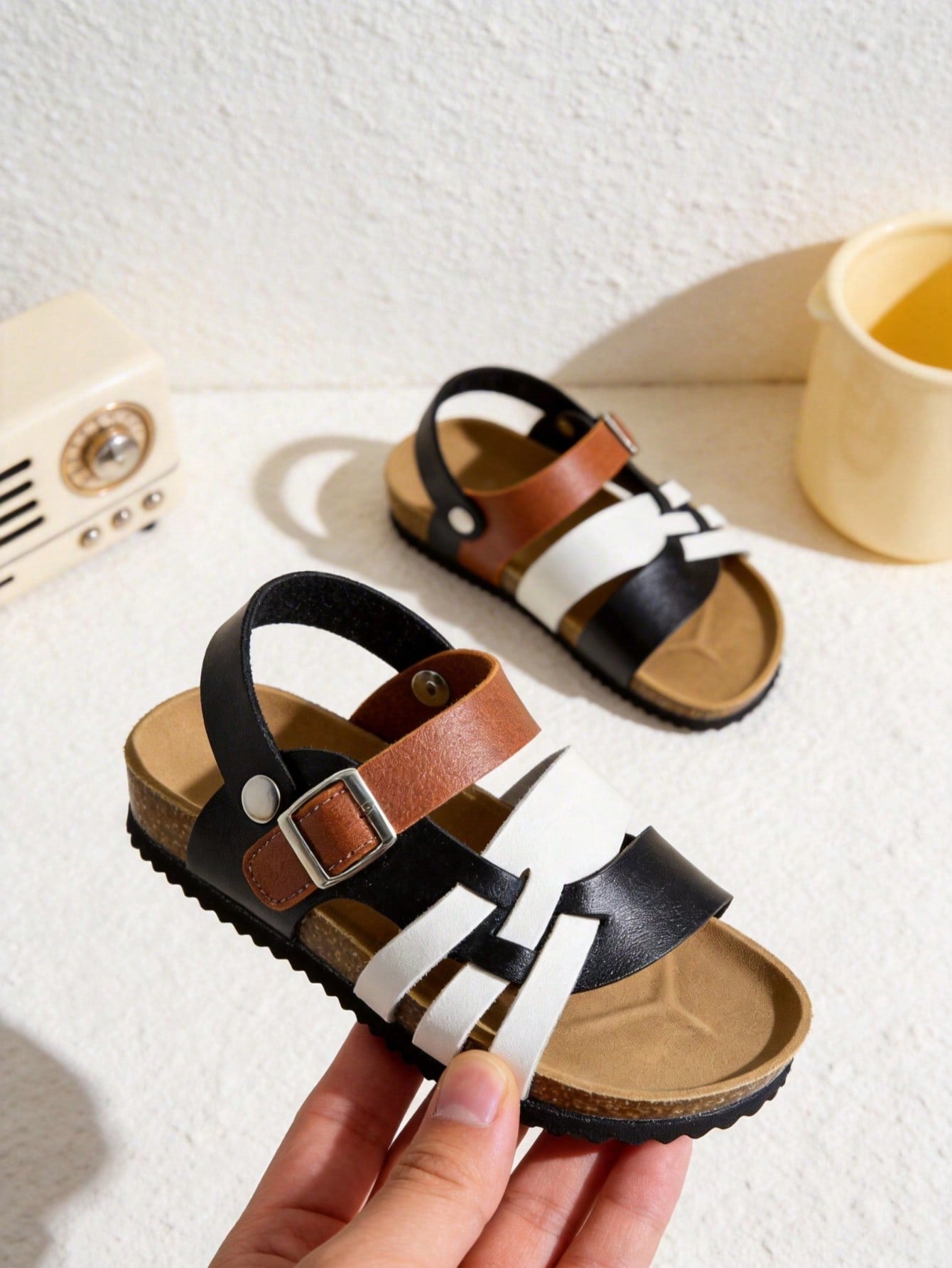 Pair of girls' pink open-toe flat sandals with ankle straps, buckle details, and a non-slip black rubber outsole.