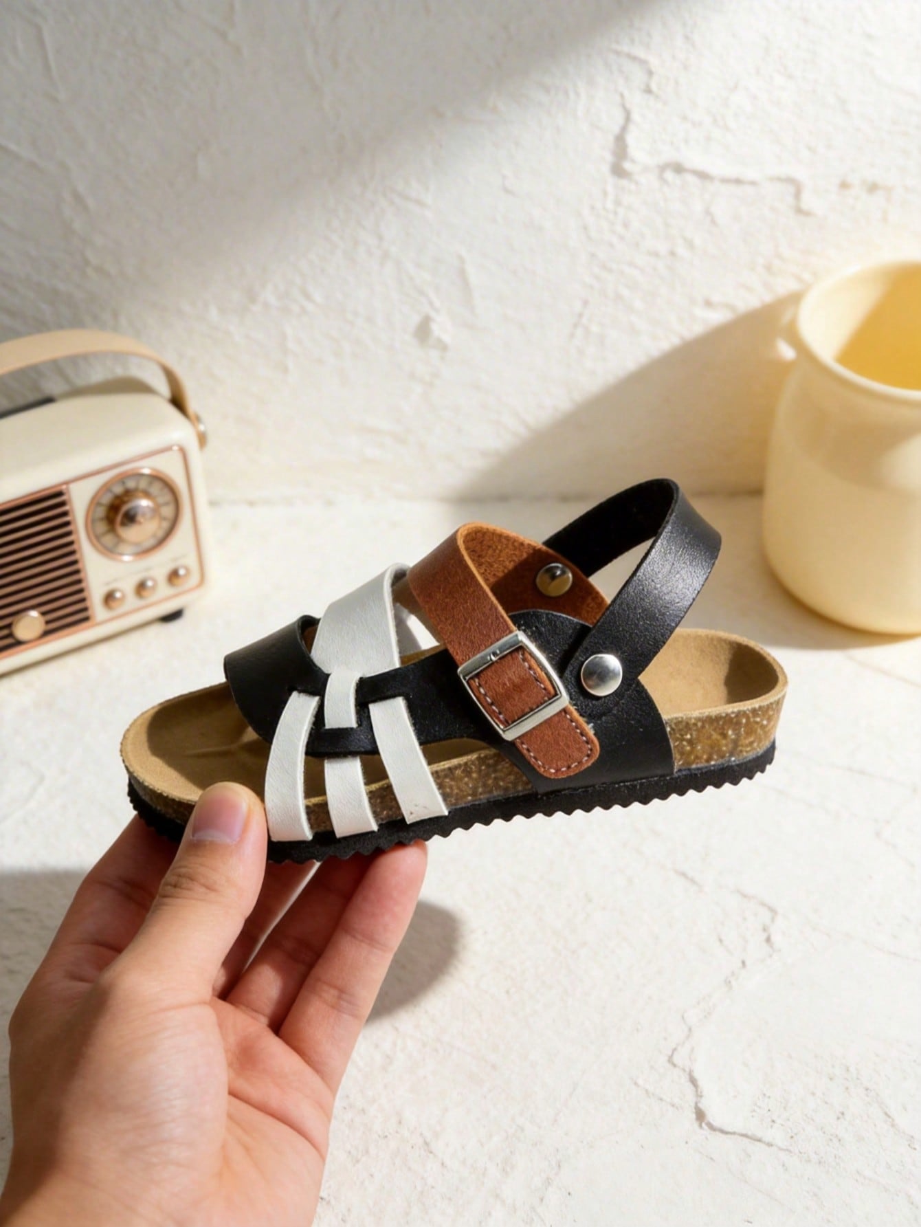 Pair of girls' pink open-toe flat sandals with ankle straps, buckle details, and a non-slip black rubber outsole.