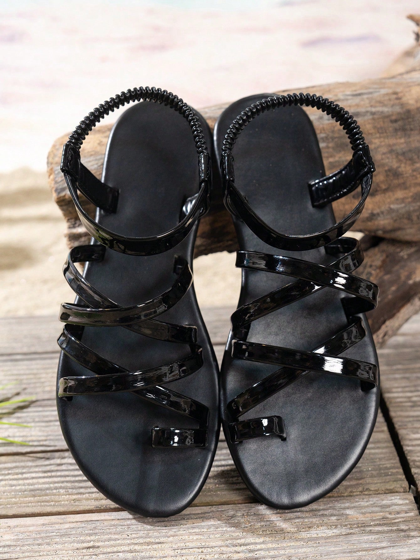 Black women's flat slide sandals with an open toe and elegant criss-cross cross-over straps, designed in a solid color beach style for casual and vacation wear.