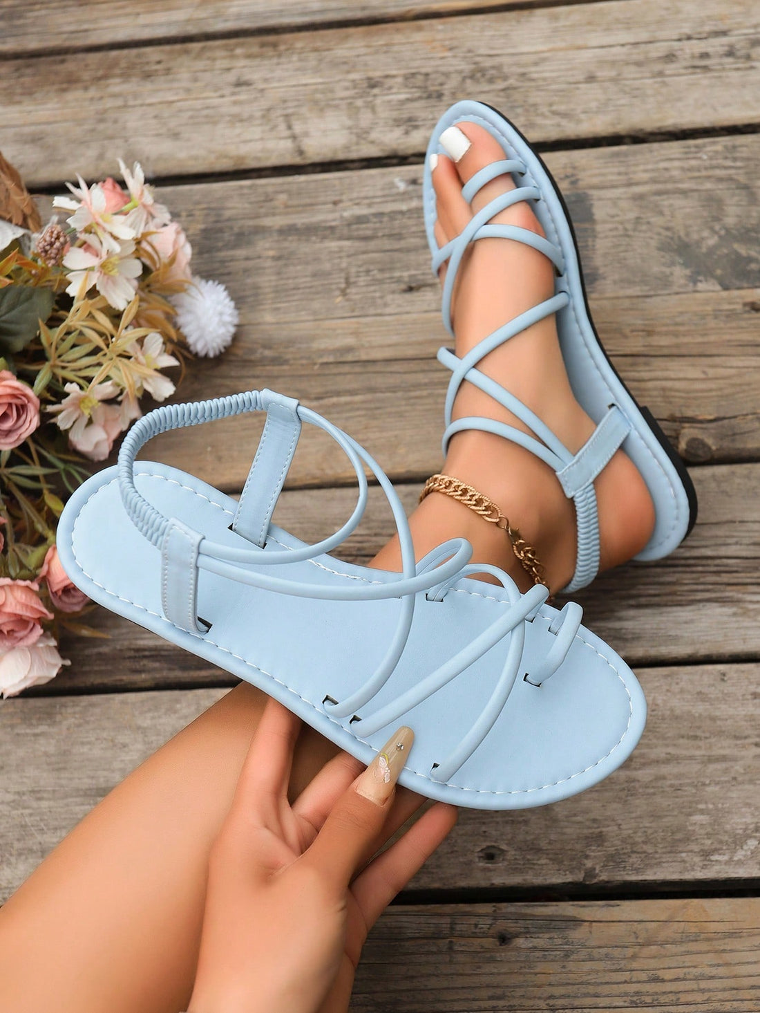 Women’s flat sandals with round toe silhouette, thin criss-cross front straps, buckle accent, and elastic back strap.
