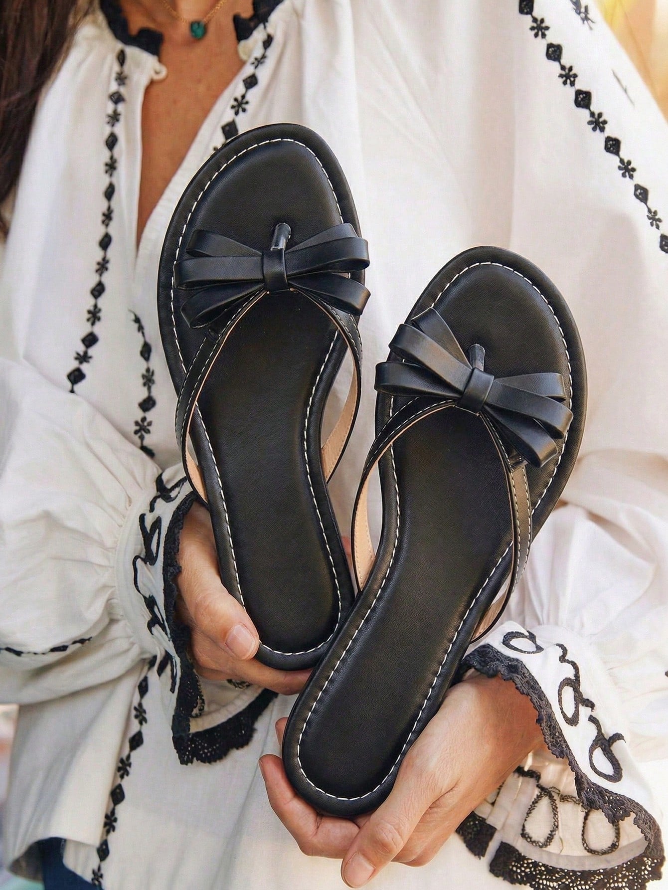 Women's flat slip-on slide sandals with textured PU leather look, bow detail on the upper, and toe-post design for casual vacation and beach wear.