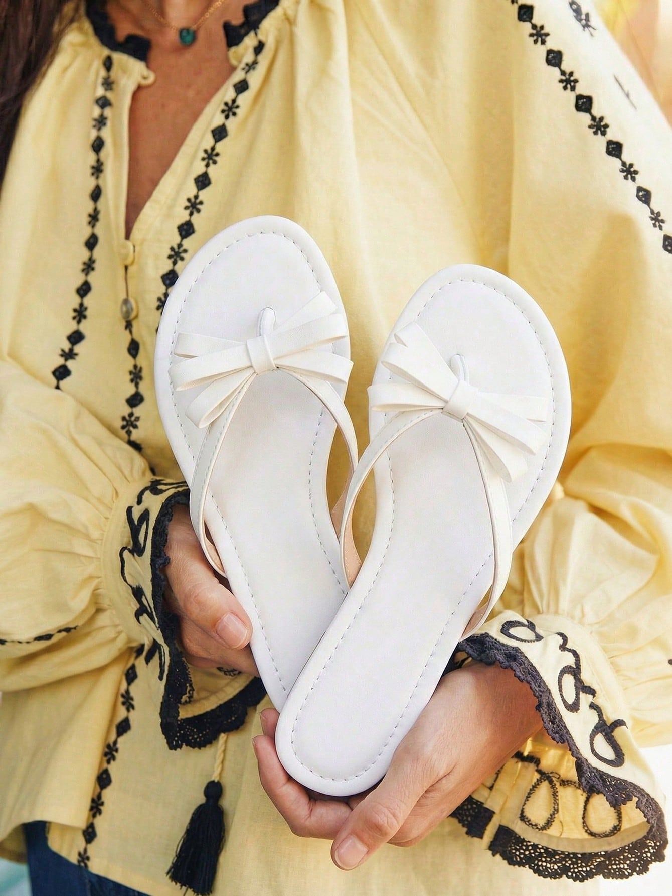 Women's flat slip-on slide sandals with textured PU leather look, bow detail on the upper, and toe-post design for casual vacation and beach wear.