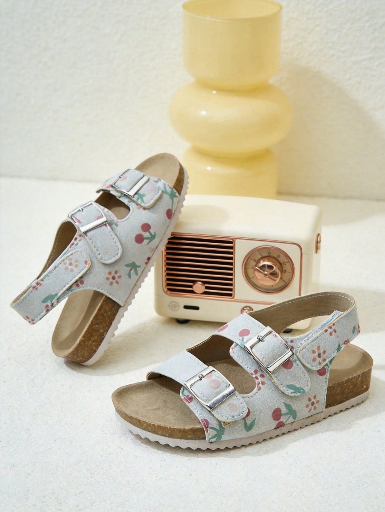 Pair of girls' pink open-toe flat sandals with ankle straps, buckle details, and a non-slip black rubber outsole.