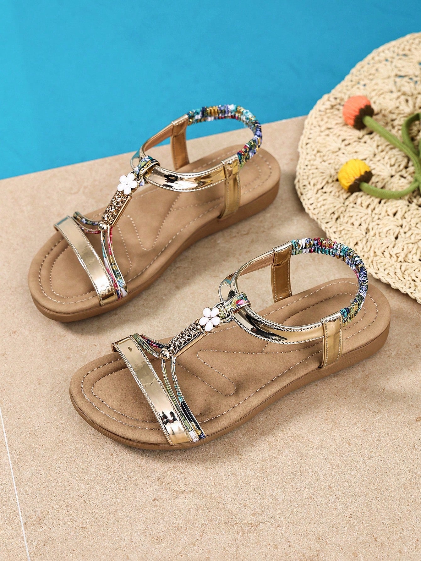 Women’s flat strappy sandals with beaded floral detail, textured pattern, elastic strap, and open-toe design.