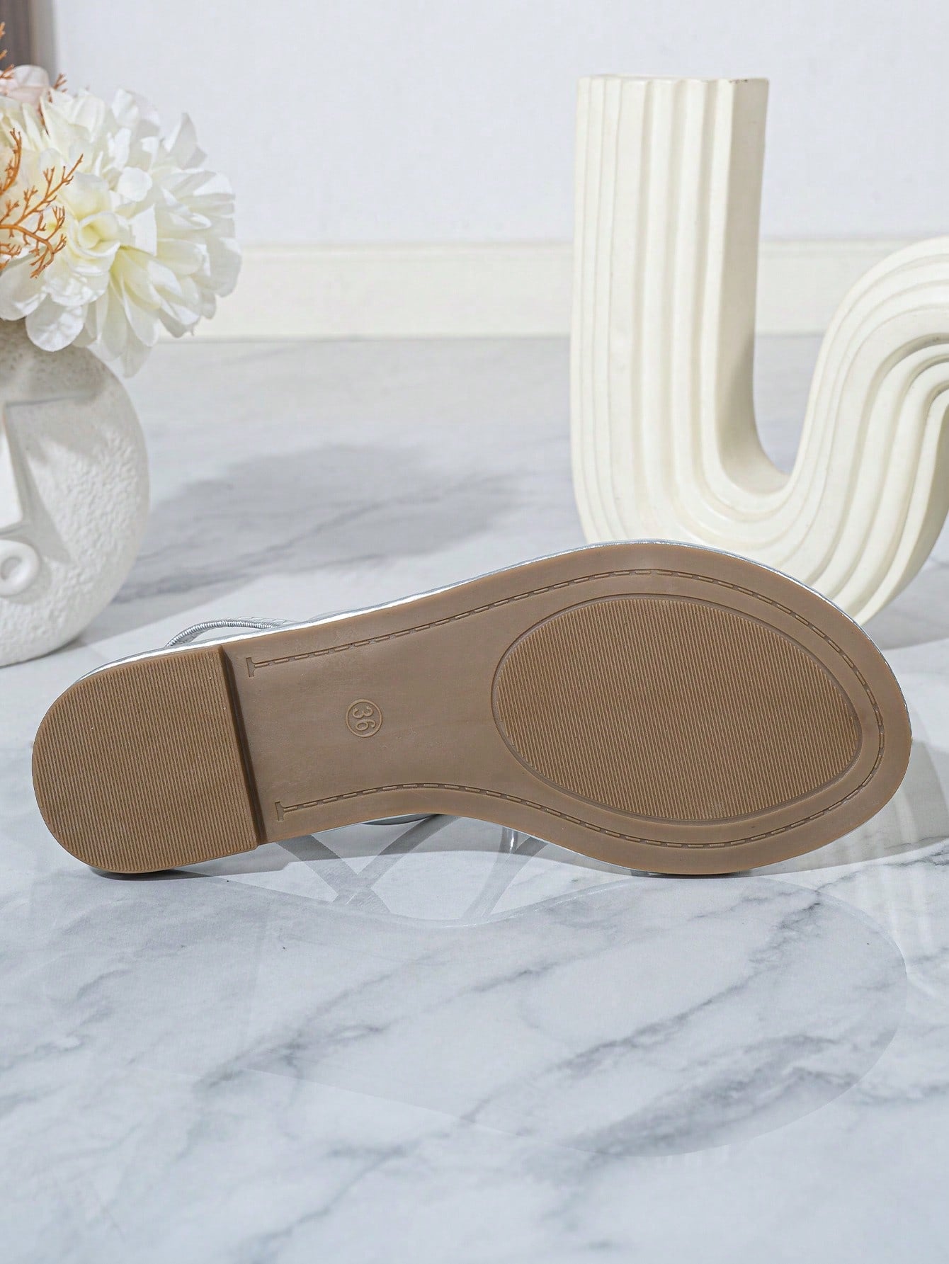 Pair of women’s gold flat sandals featuring a toe ring thong toe post design, criss-cross straps, and a slingback ankle strap.