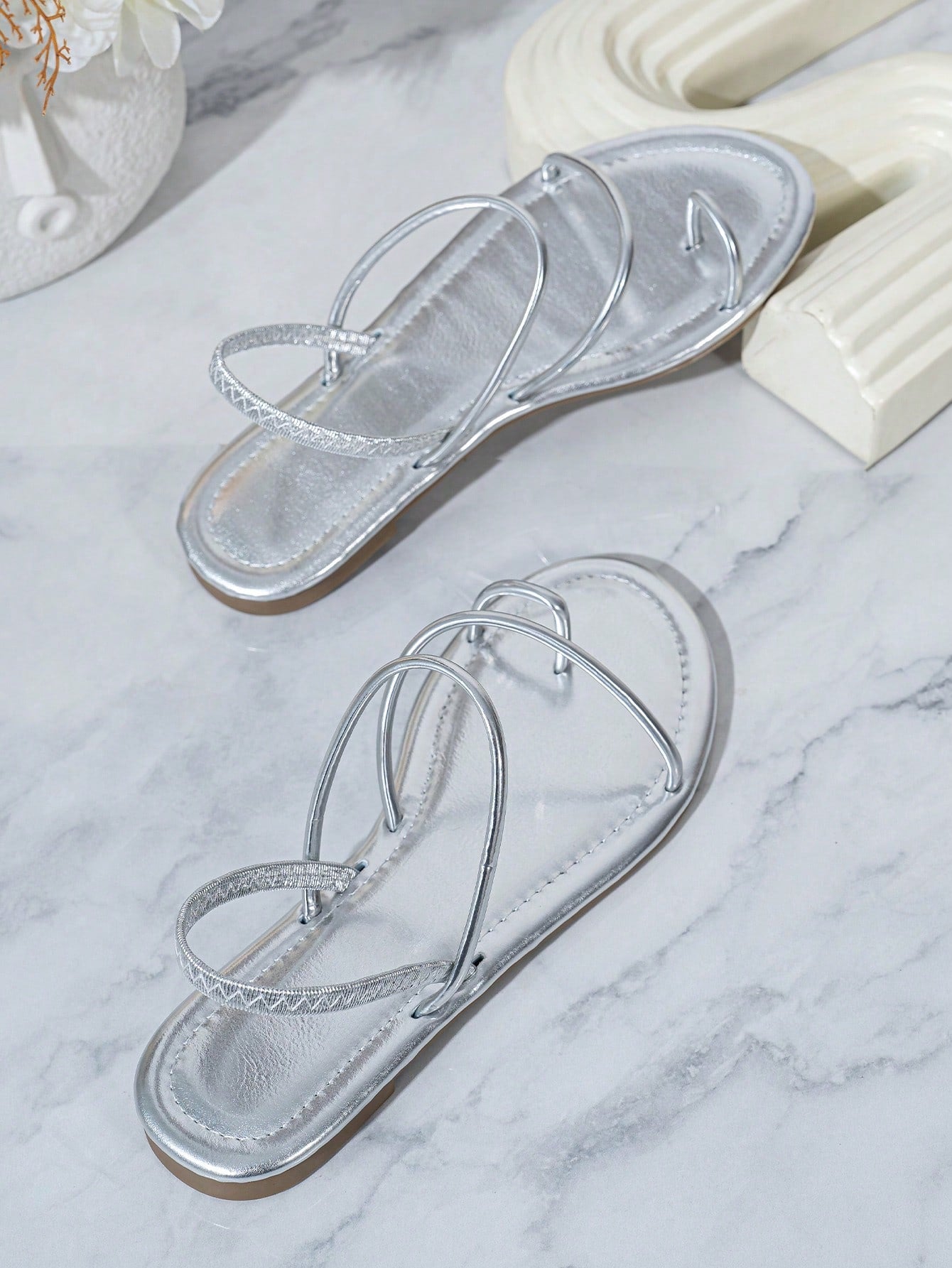 Pair of women’s gold flat sandals featuring a toe ring thong toe post design, criss-cross straps, and a slingback ankle strap.