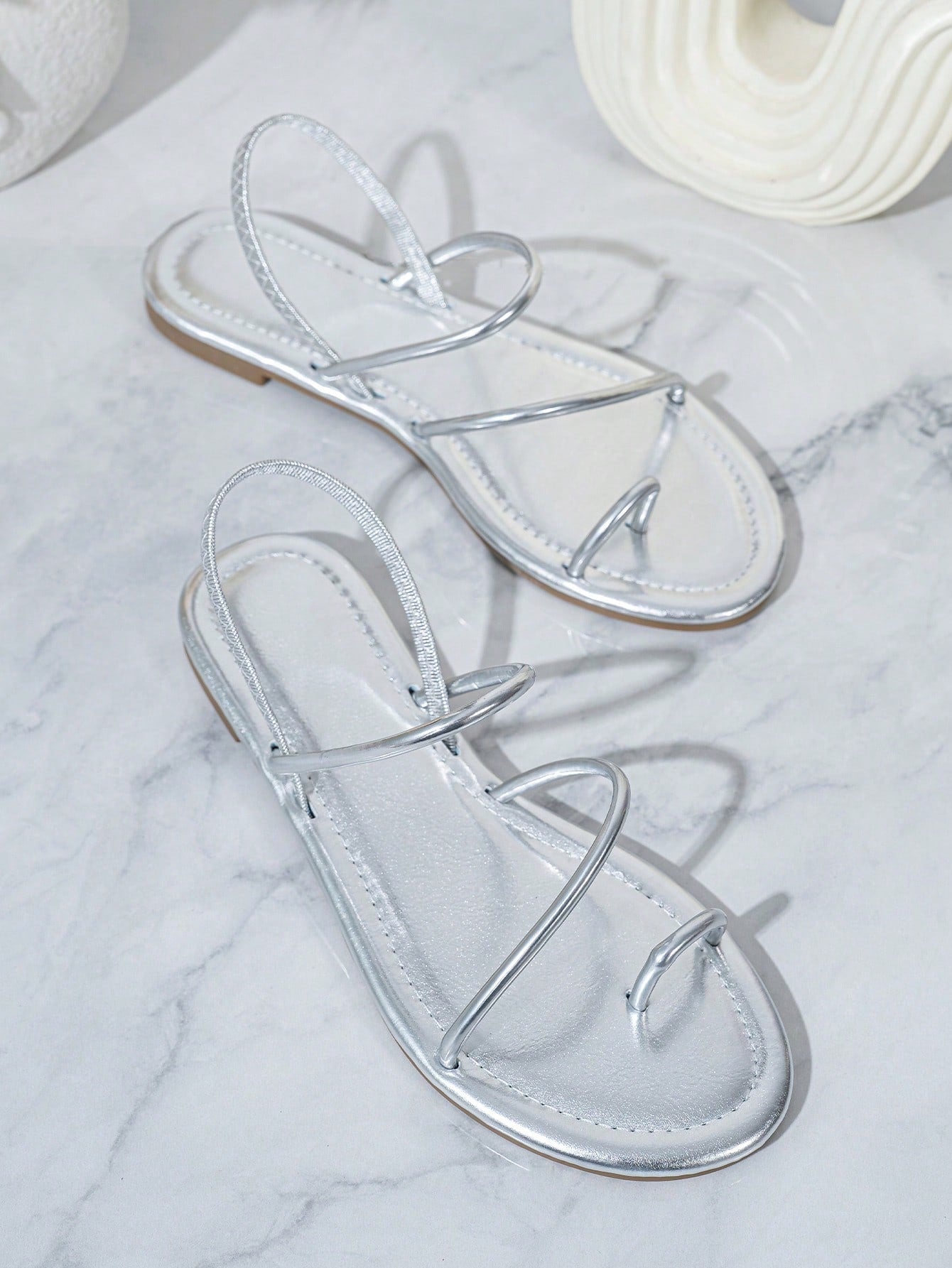 Pair of women’s gold flat sandals featuring a toe ring thong toe post design, criss-cross straps, and a slingback ankle strap.