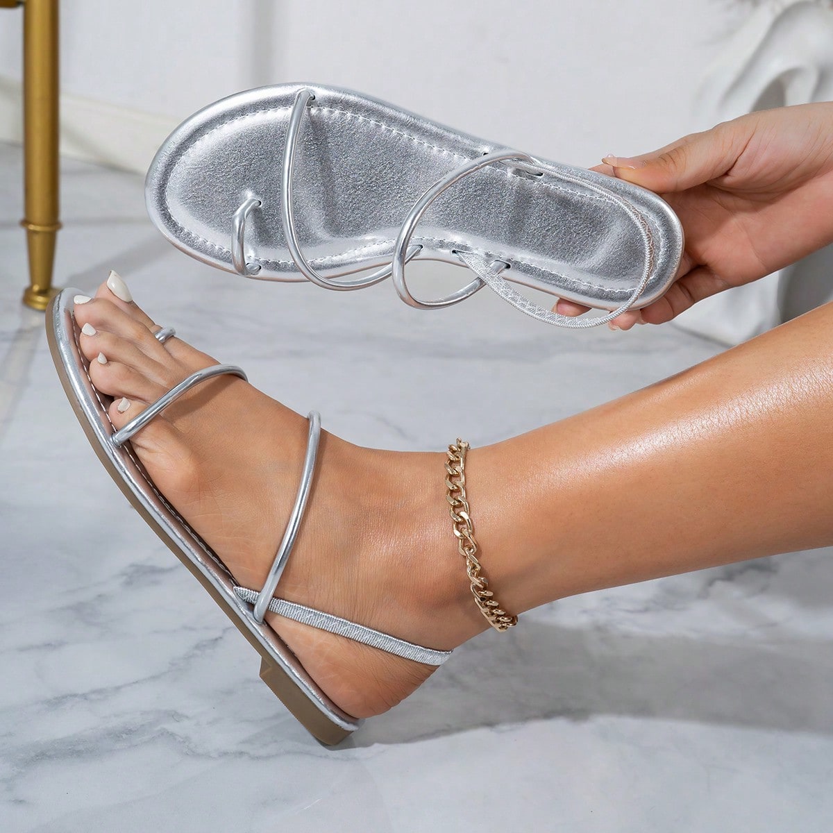 Pair of women’s gold flat sandals featuring a toe ring thong toe post design, criss-cross straps, and a slingback ankle strap.