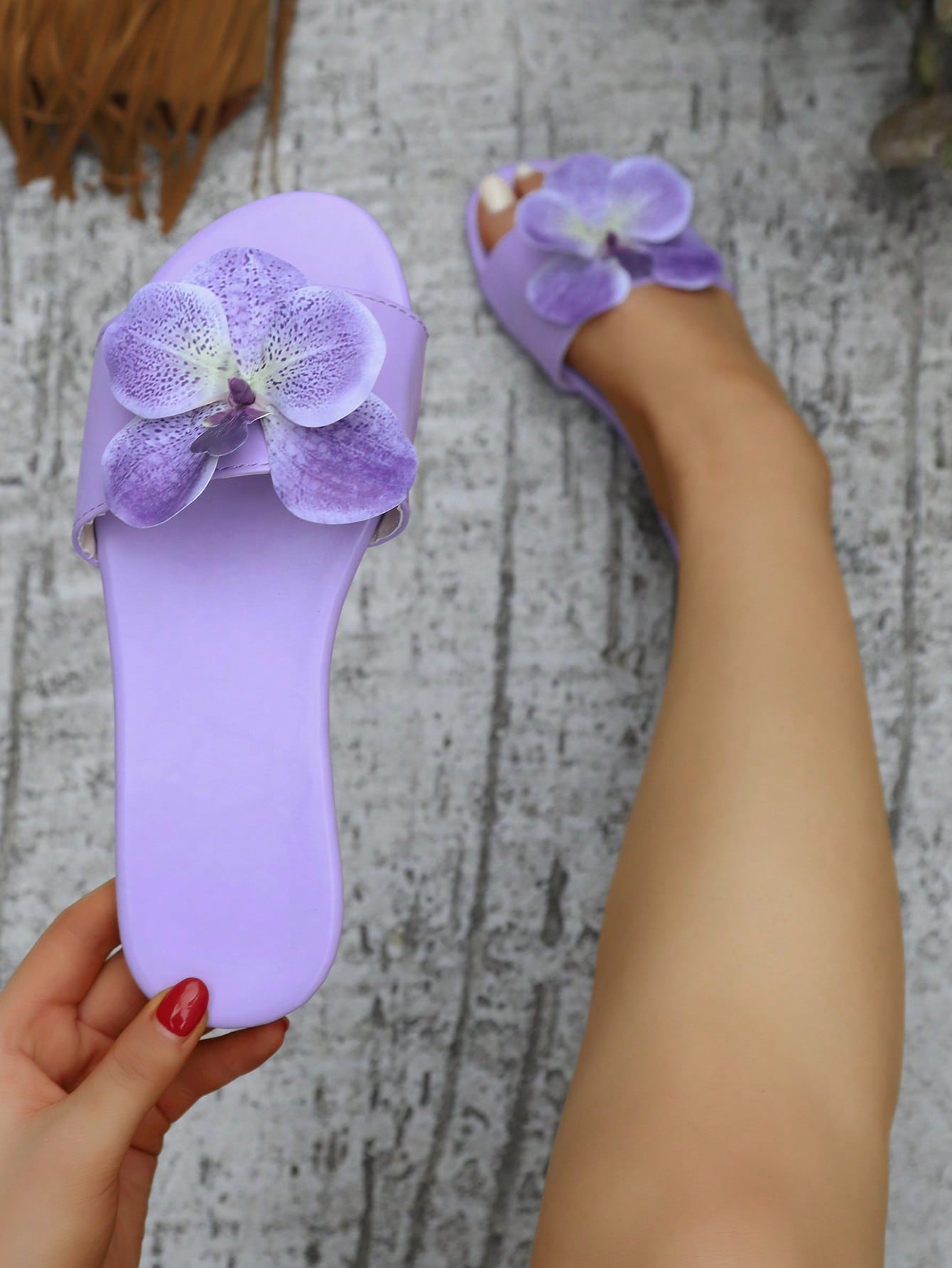 Women’s open toe flat toe-ring slide sandals with artificial flower applique detail and vacation beach style.