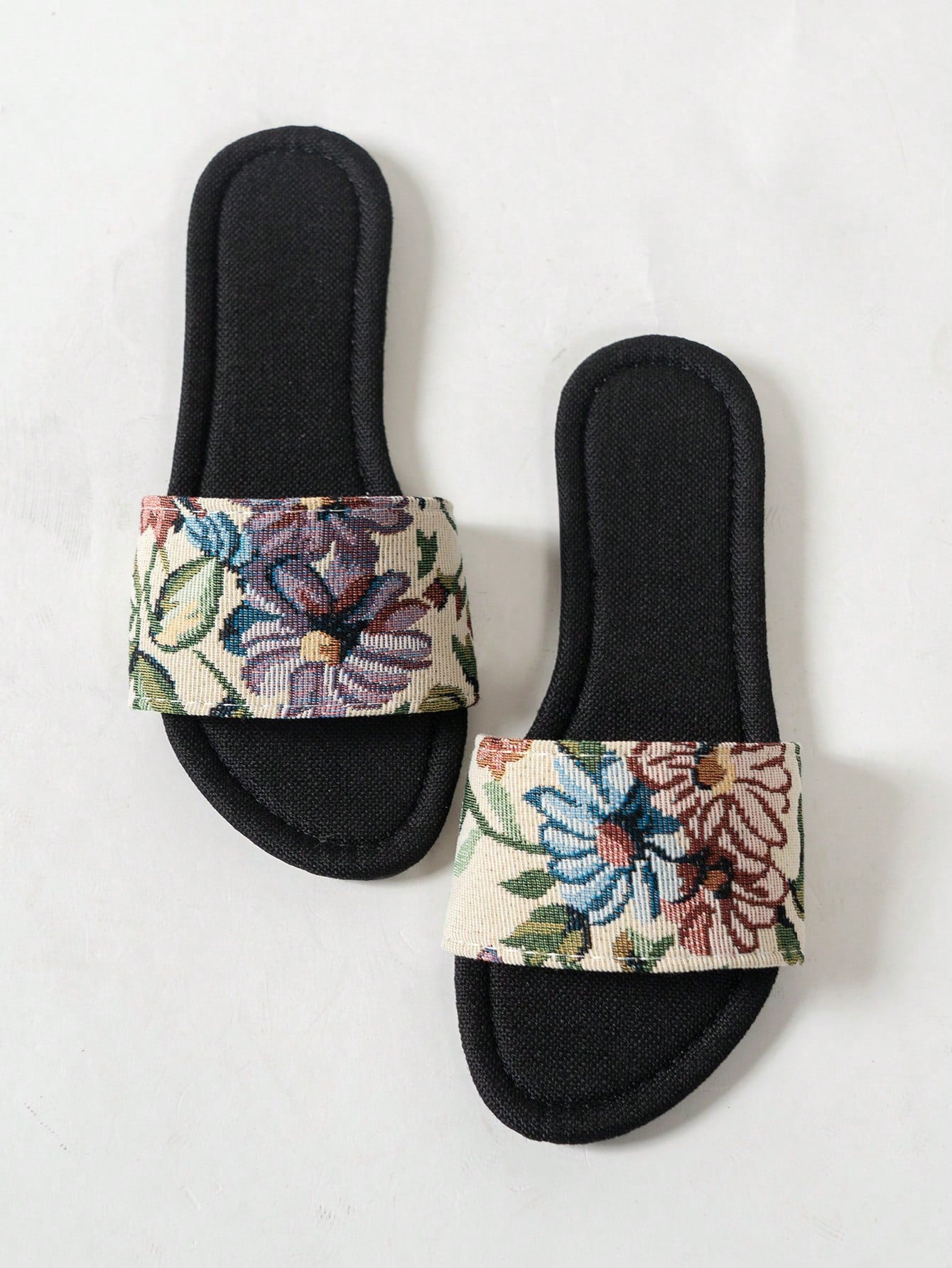 Women’s flat slide sandals featuring a floral printed strap and open toe design in a minimal style.
