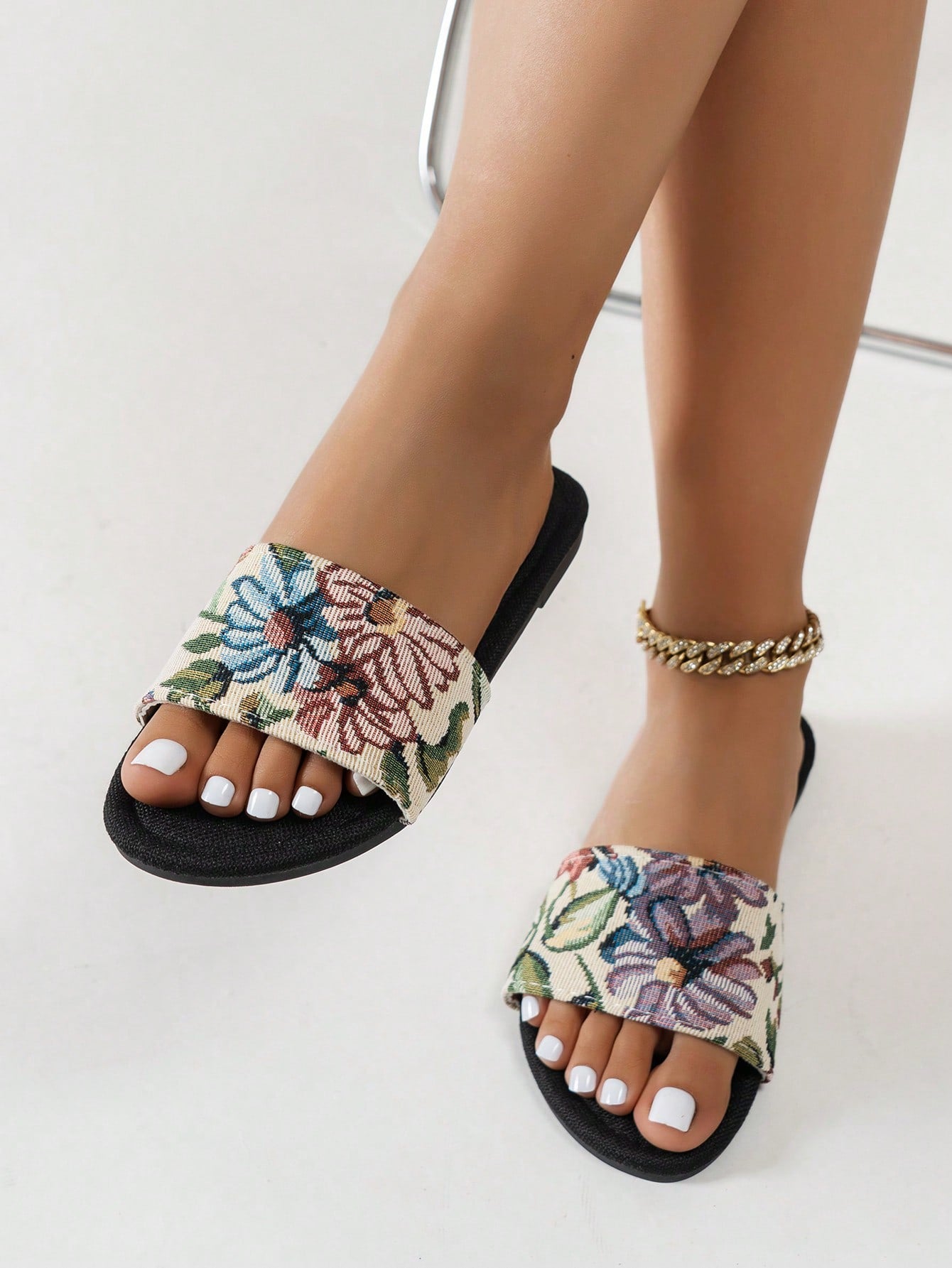 Women’s flat slide sandals featuring a floral printed strap and open toe design in a minimal style.