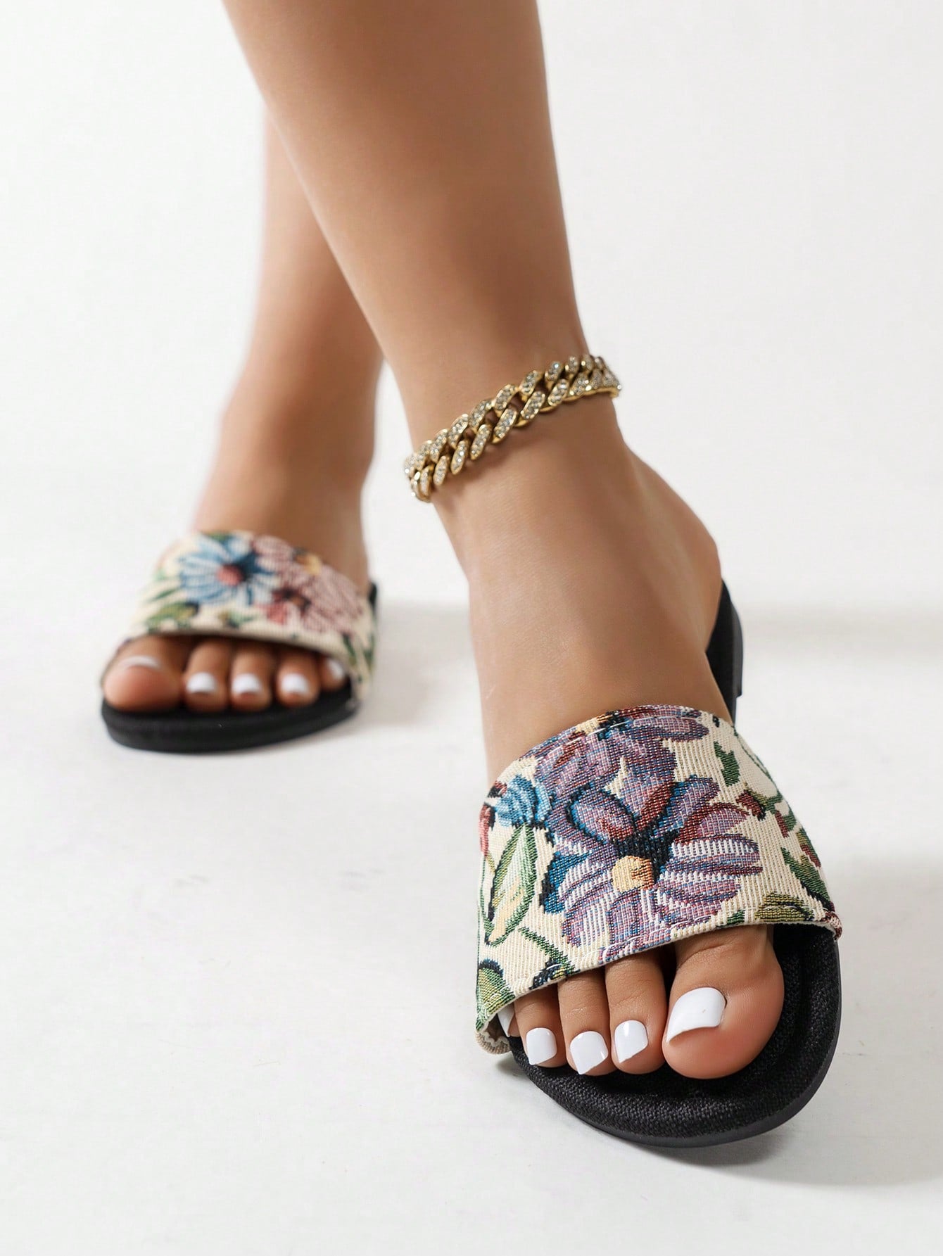 Women’s flat slide sandals featuring a floral printed strap and open toe design in a minimal style.