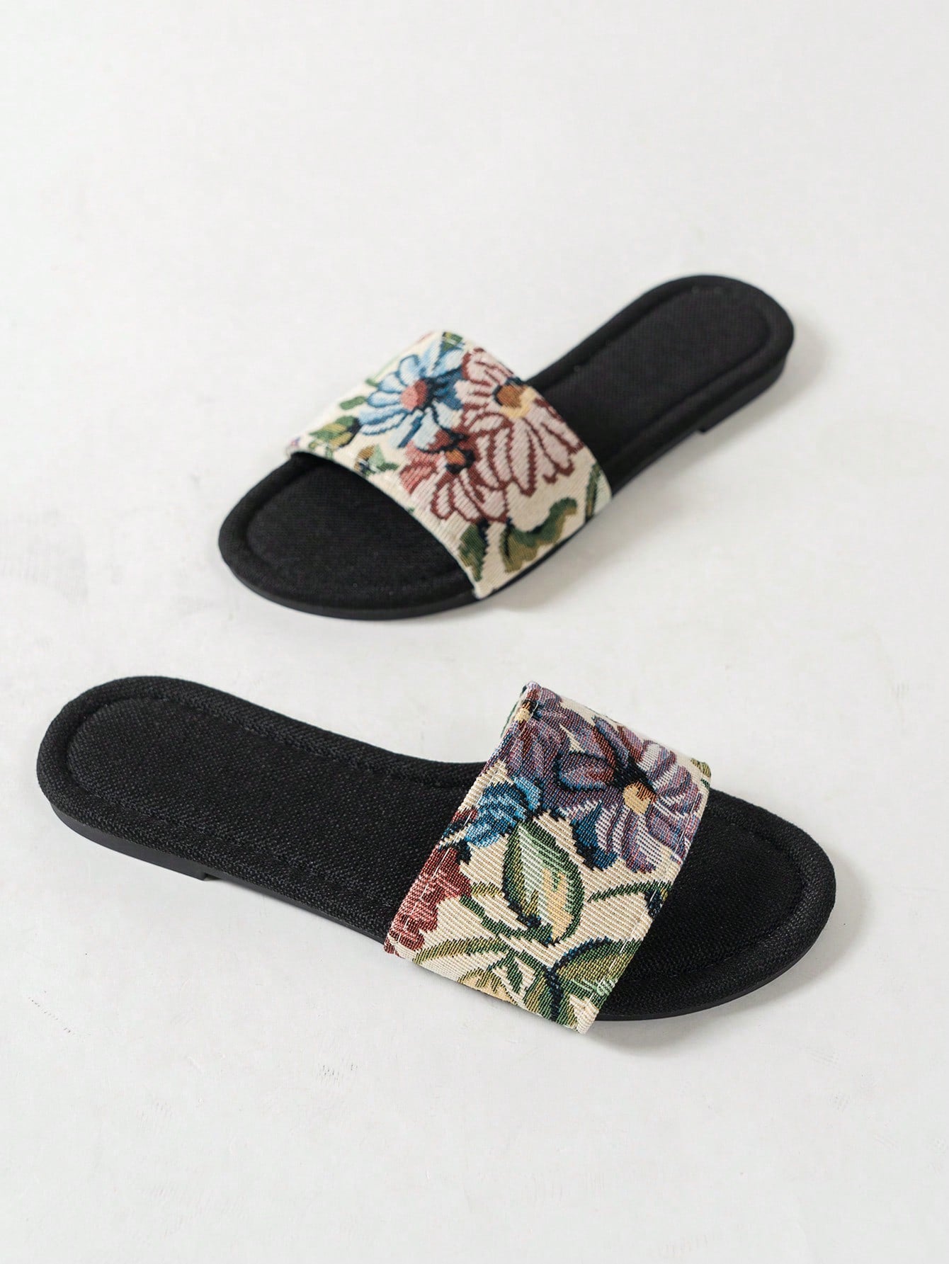 Women’s flat slide sandals featuring a floral printed strap and open toe design in a minimal style.