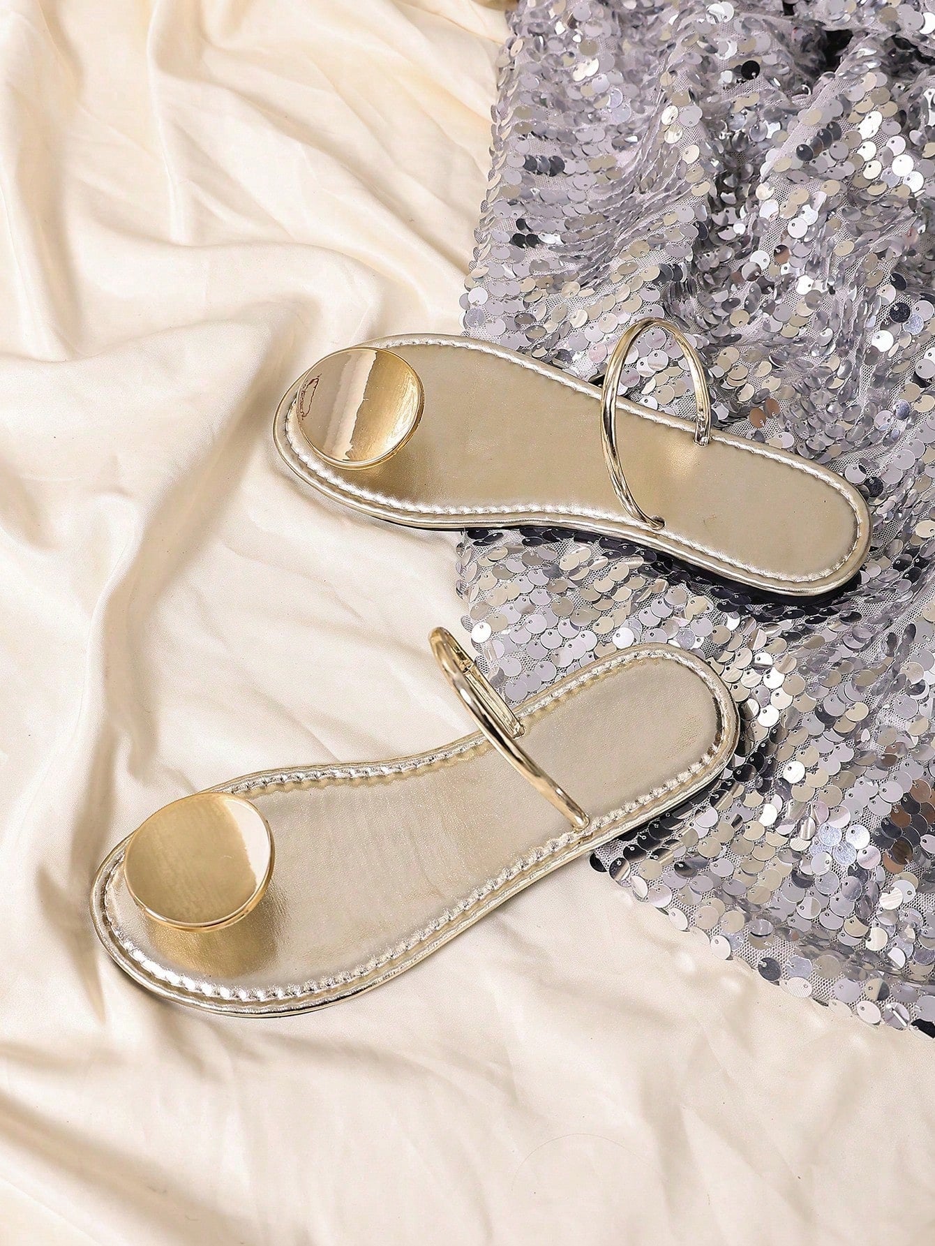 Women’s flat thong sandals with a shiny round buckle, high-gloss finish, semi-circle strap, and toe post design