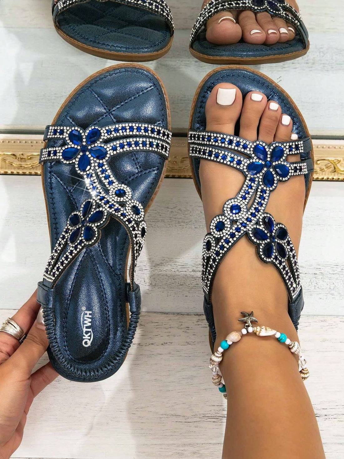 Navy blue women's flat gladiator sandals with rhinestone and cut-out details, elastic band straps, and an open toe design.