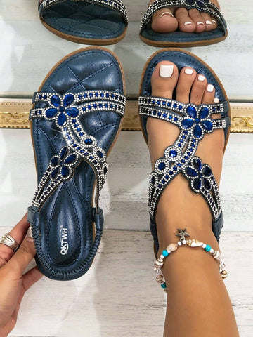 Navy blue women's flat gladiator sandals with rhinestone and cut-out details, elastic band straps, and an open toe design.