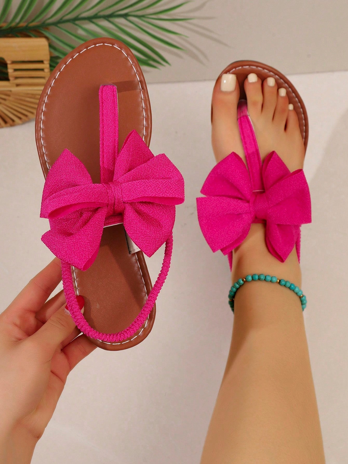 Pair of women’s solid color bohemian flat sandals with fabric bow detail, toe post thong design, and slide-on style for casual beach, outdoor, vacation, and home wear.