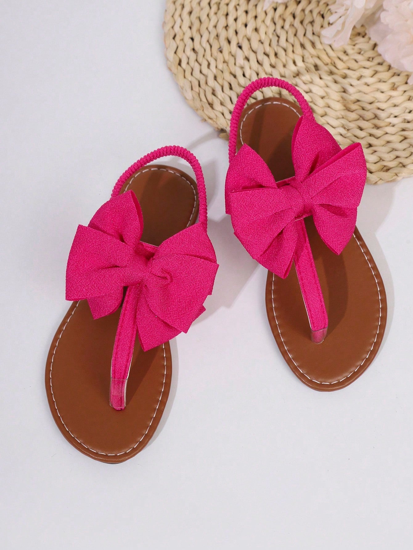 Pair of women’s solid color bohemian flat sandals with fabric bow detail, toe post thong design, and slide-on style for casual beach, outdoor, vacation, and home wear.