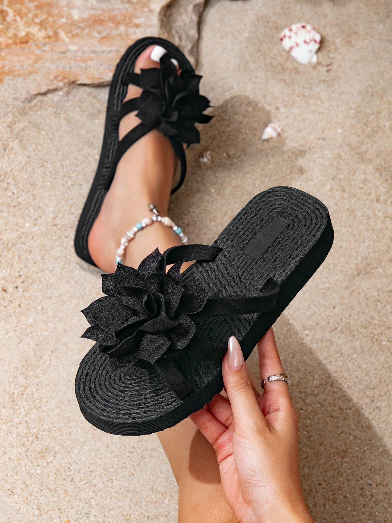 Women's woven-style flat beach flip-flop sandals with black peony applique decoration and casual design
