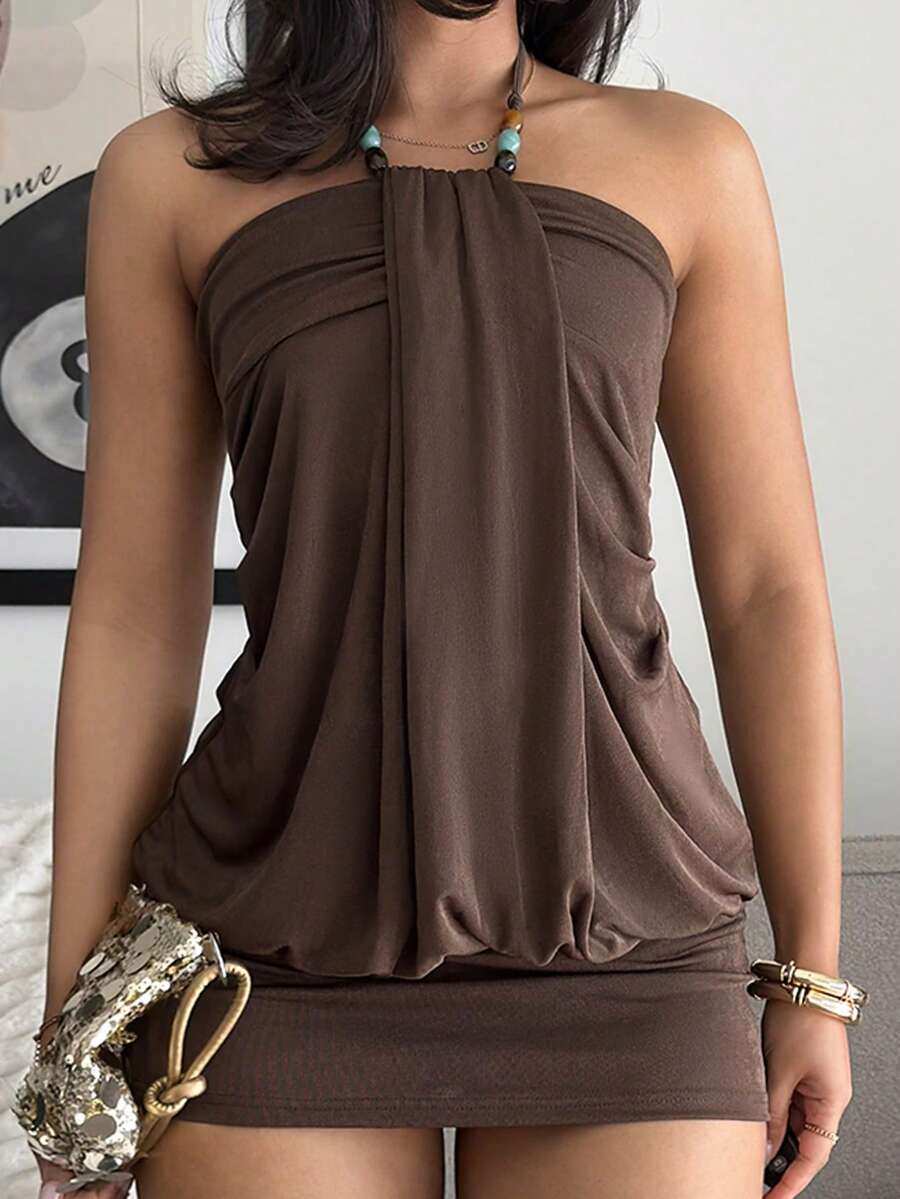 Women's coffee mini dress with halter neckline, backless draped design, sleeveless slim fit silhouette, straight hem, and high-stretch knitted fabric.