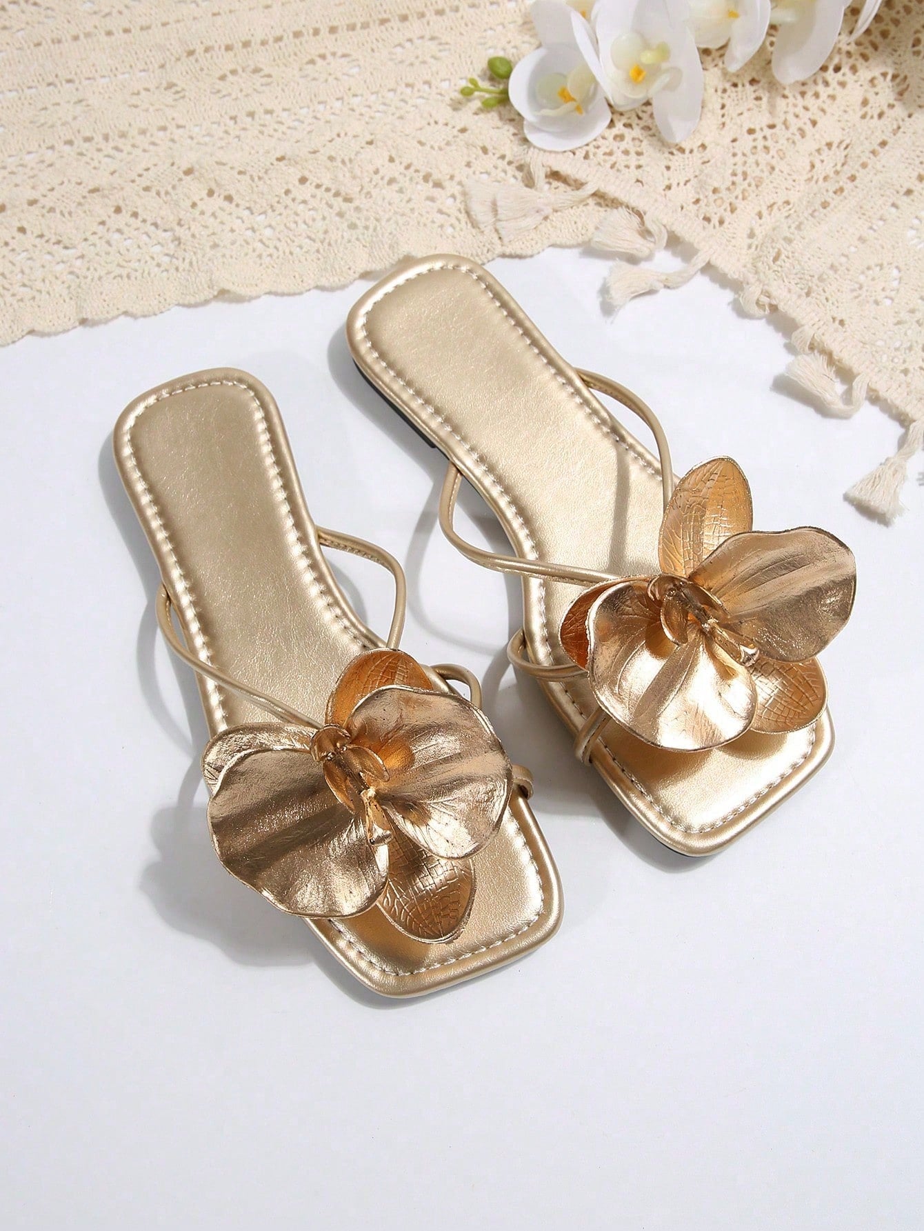 Women's flat slide sandals with open toe, floral applique detail, and criss-cross straps, shown as casual vacation-style summer footwear.