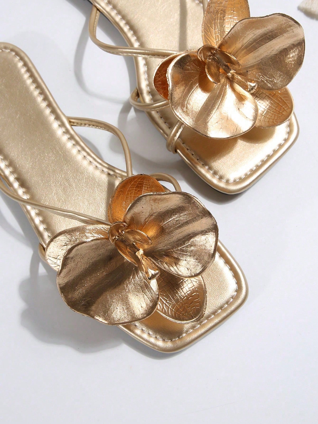 Women's flat slide sandals with open toe, floral applique detail, and criss-cross straps, shown as casual vacation-style summer footwear.