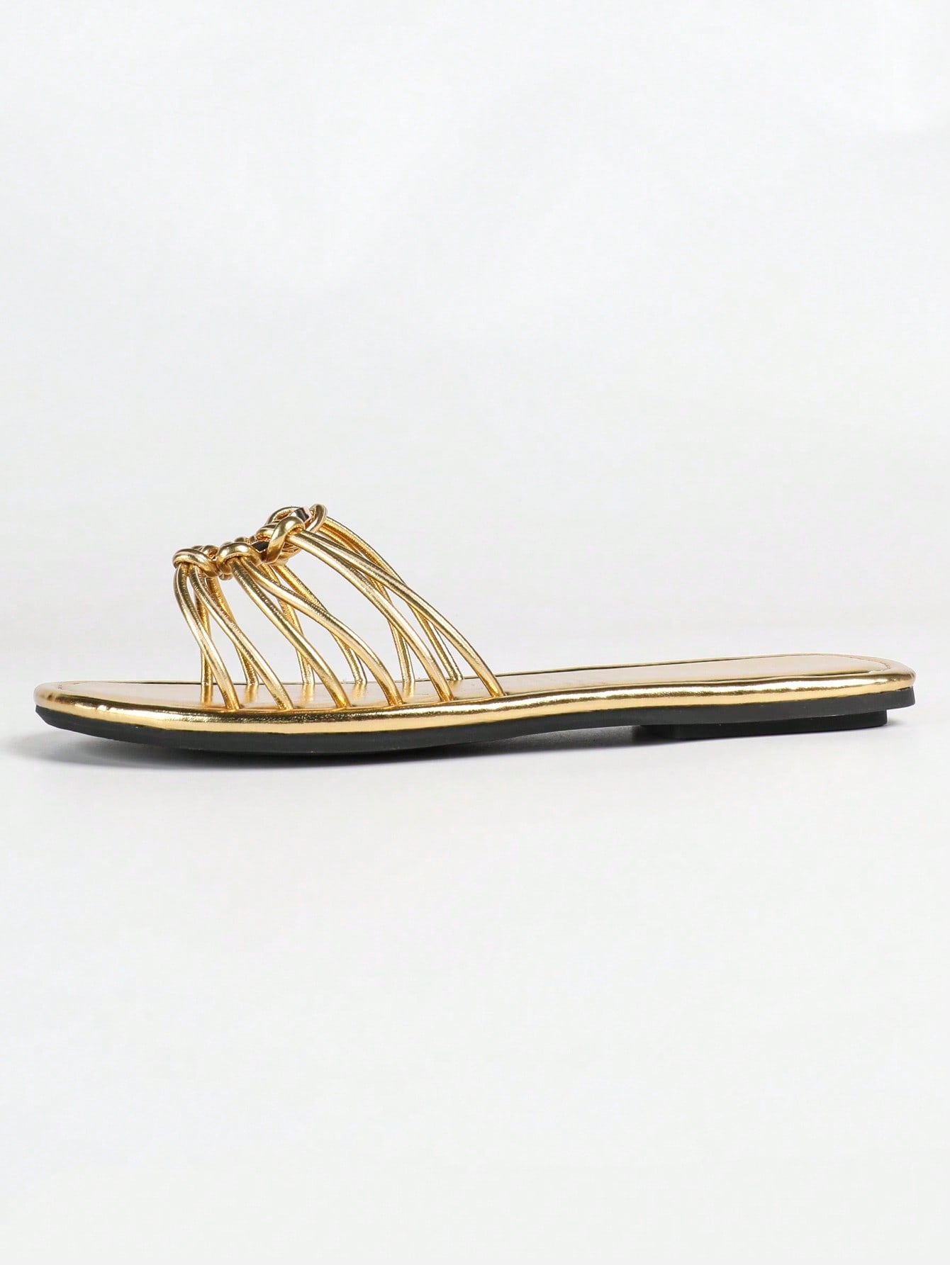 Women's gold flat sandals with metal accent detail, strappy lace-up design, and toe post thong style.