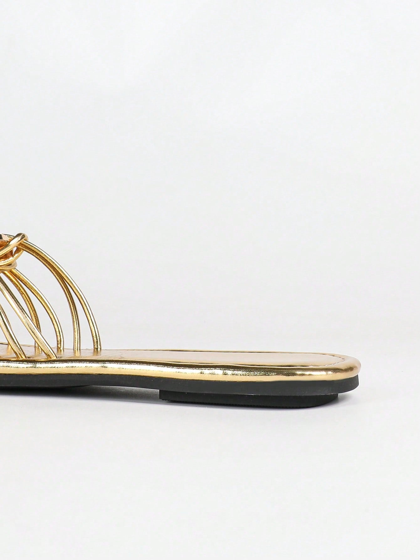 Women's gold flat sandals with metal accent detail, strappy lace-up design, and toe post thong style.