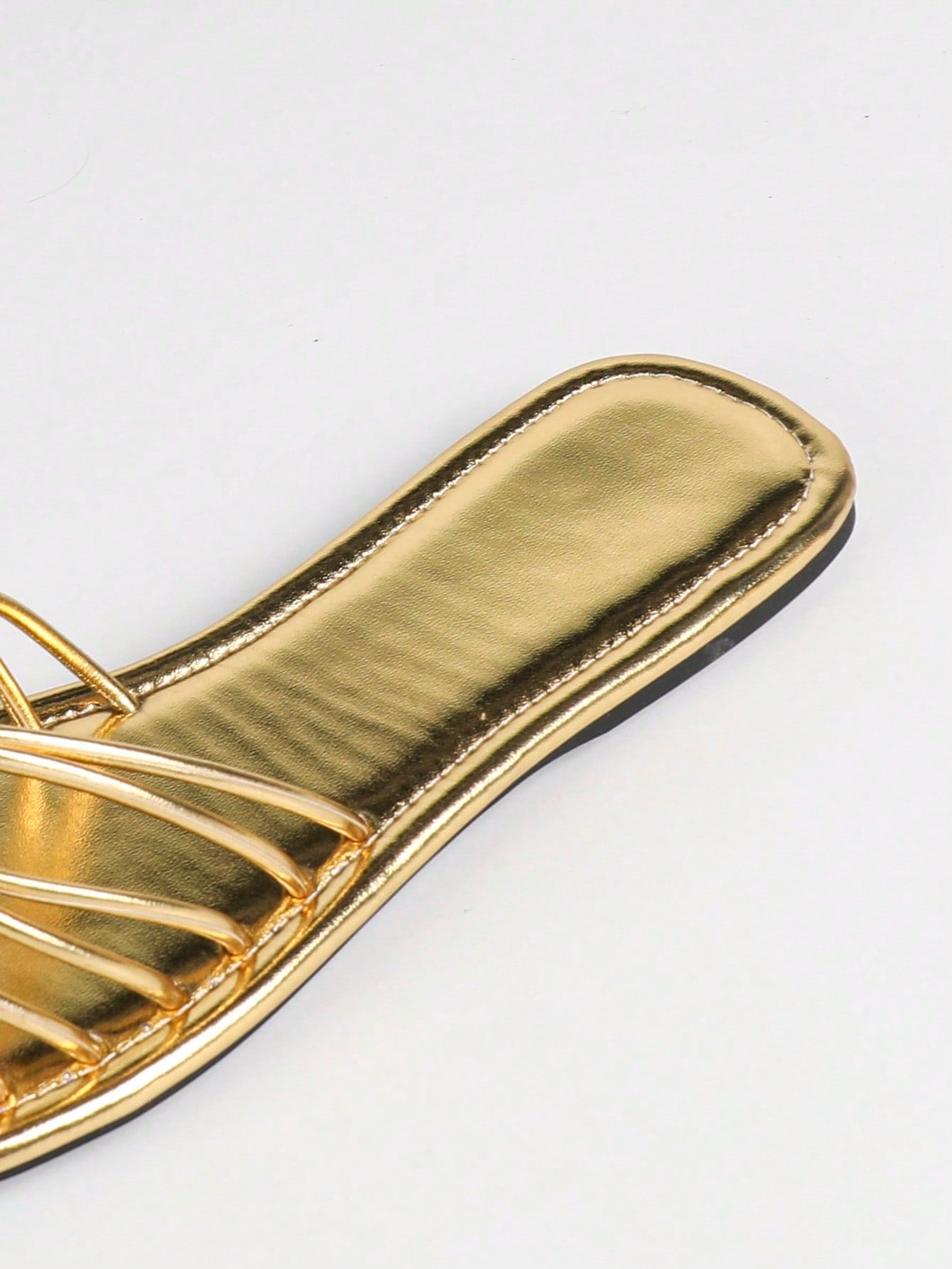 Women's gold flat sandals with metal accent detail, strappy lace-up design, and toe post thong style.