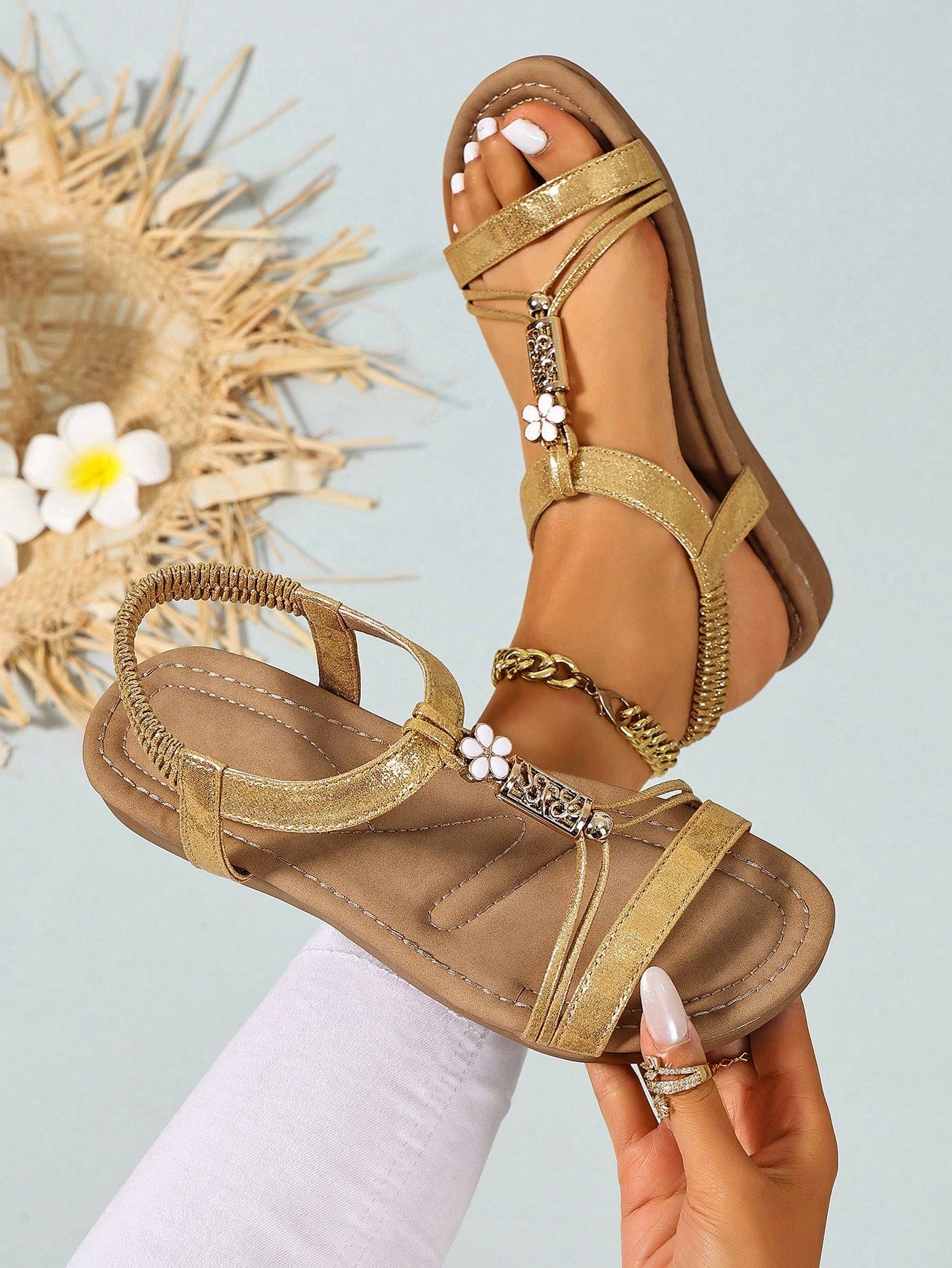 Women’s flat strappy sandals with beaded floral detail, textured pattern, elastic strap, and open-toe design.
