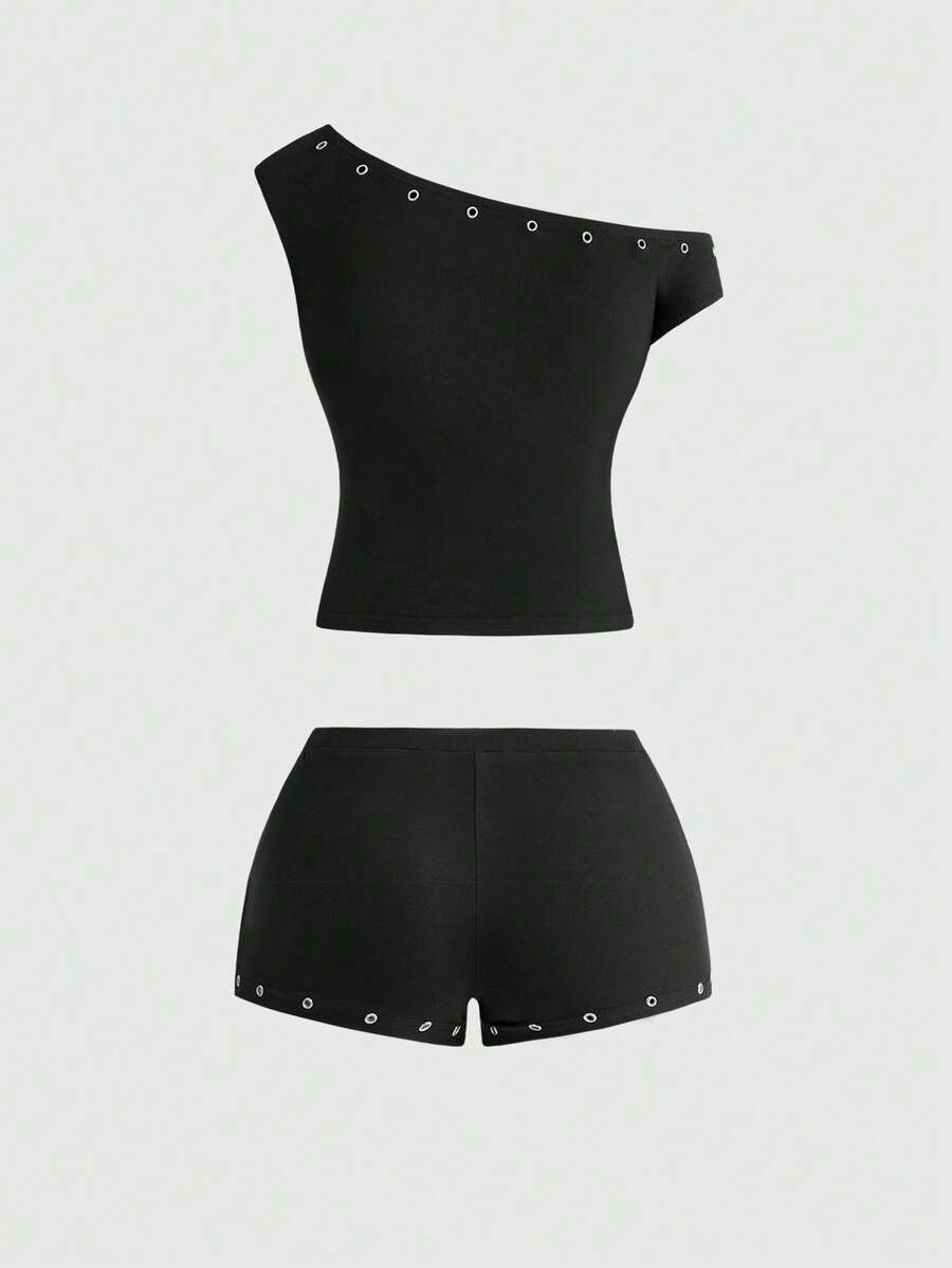 Women's two-piece outfit with an asymmetric neck studded grommet crop top and super low-rise mini shorts