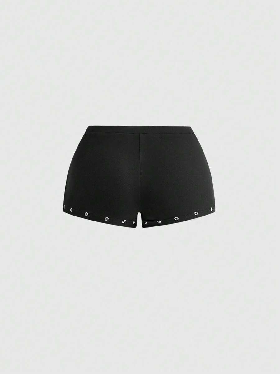 Women's two-piece outfit with an asymmetric neck studded grommet crop top and super low-rise mini shorts