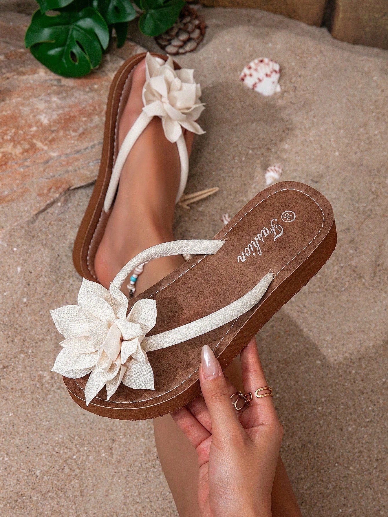 Women's woven-style flat beach flip-flop sandals with black peony applique decoration and casual design