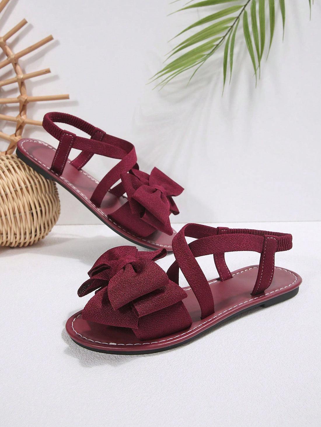 Plus size women's burgundy flat gladiator sandals with open toe, criss-cross elastic straps, and big bow detail, slip-on style for beach and summer outdoor wear.