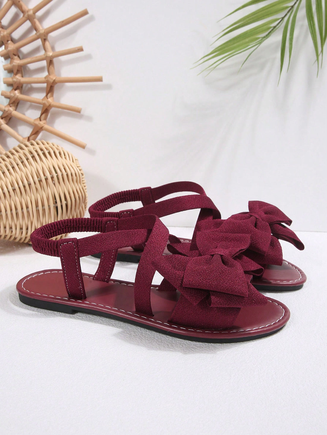 Plus size women's burgundy flat gladiator sandals with open toe, criss-cross elastic straps, and big bow detail, slip-on style for beach and summer outdoor wear.