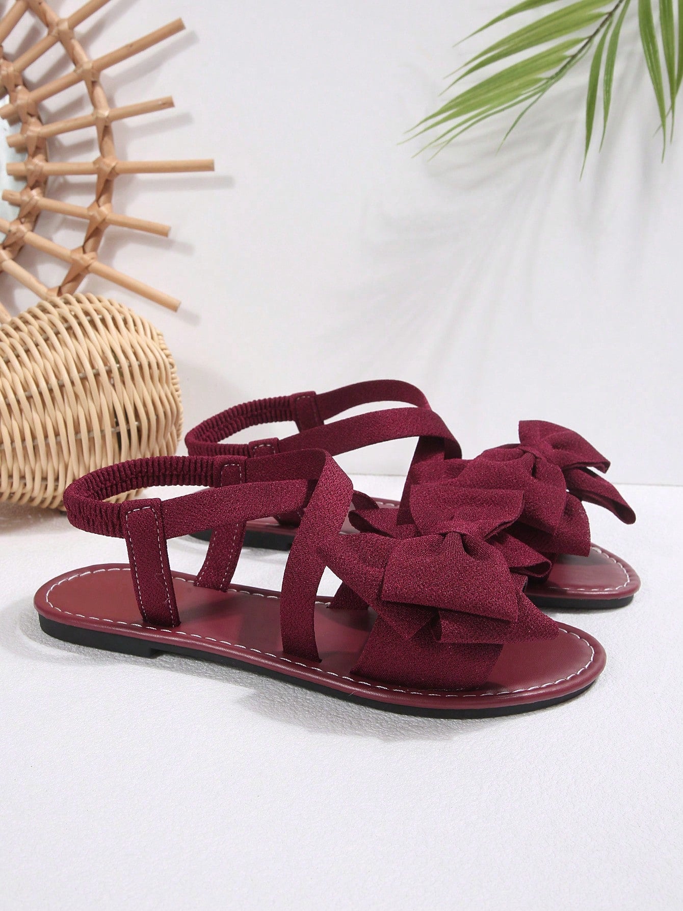 Plus size women's burgundy flat gladiator sandals with open toe, criss-cross elastic straps, and big bow detail, slip-on style for beach and summer outdoor wear.