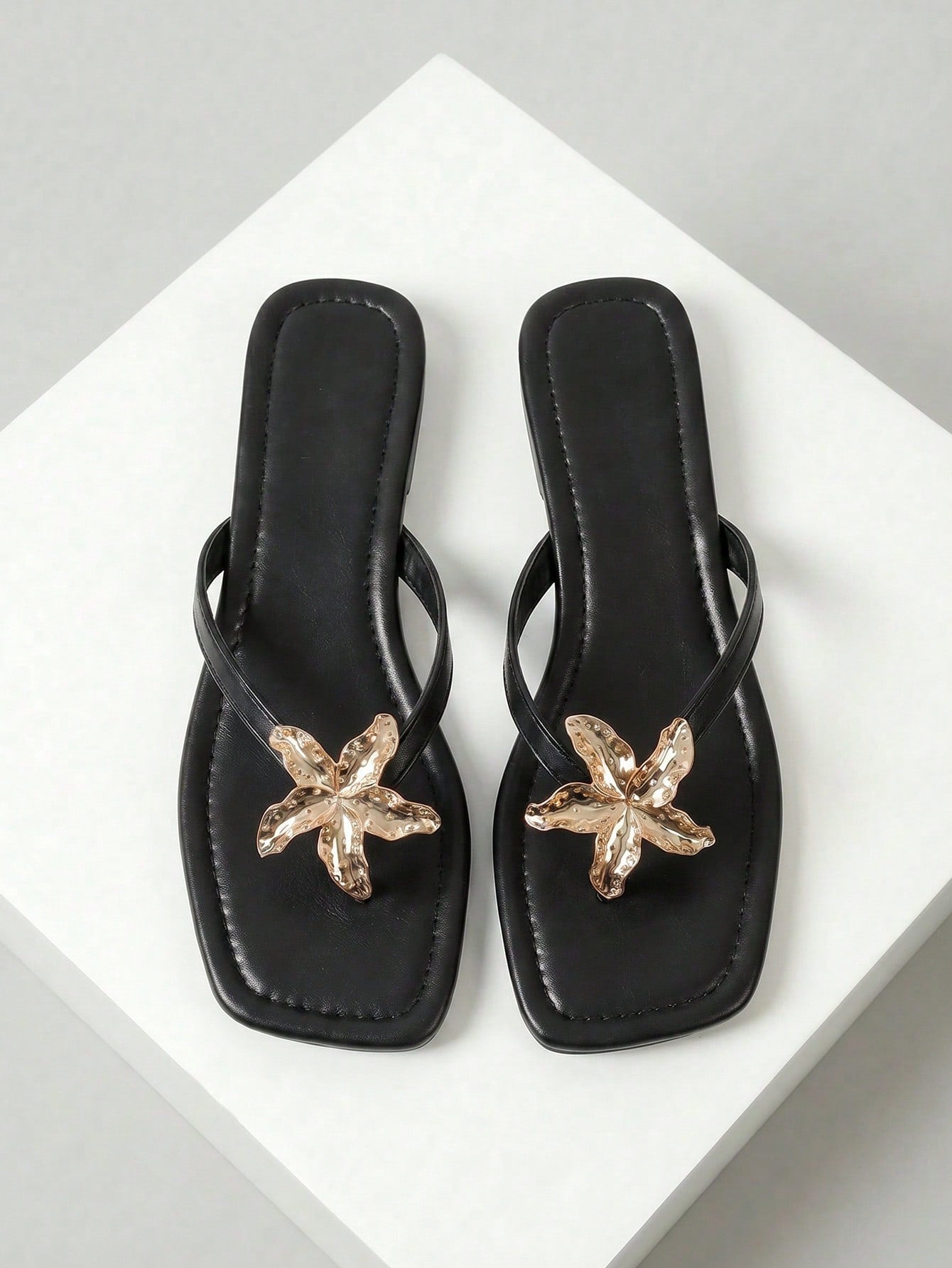 Women's black flat slide sandals with toe post design, textured PU leather straps, and rhinestone heart decoration.