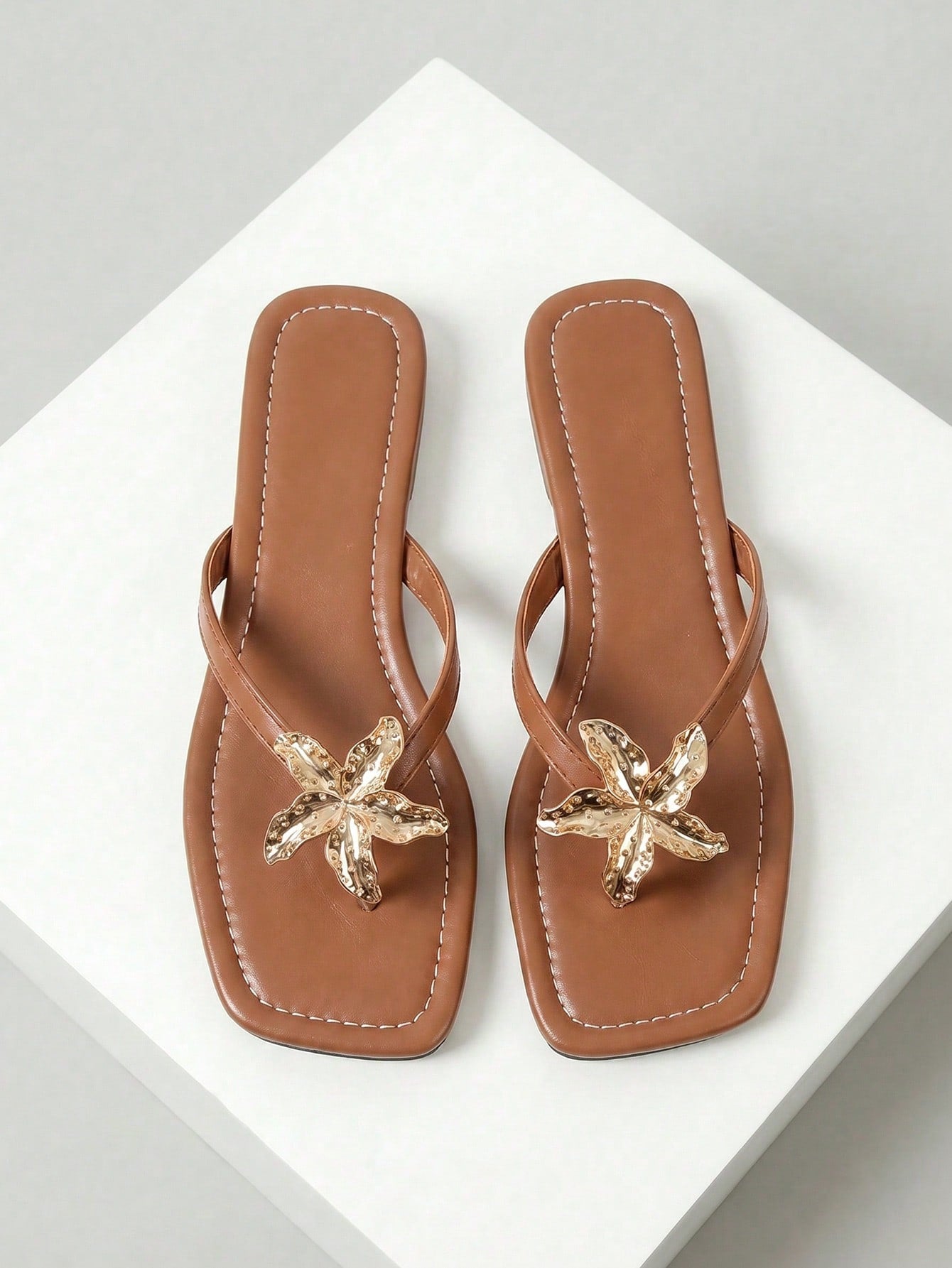 Women's black flat slide sandals with toe post design, textured PU leather straps, and rhinestone heart decoration.
