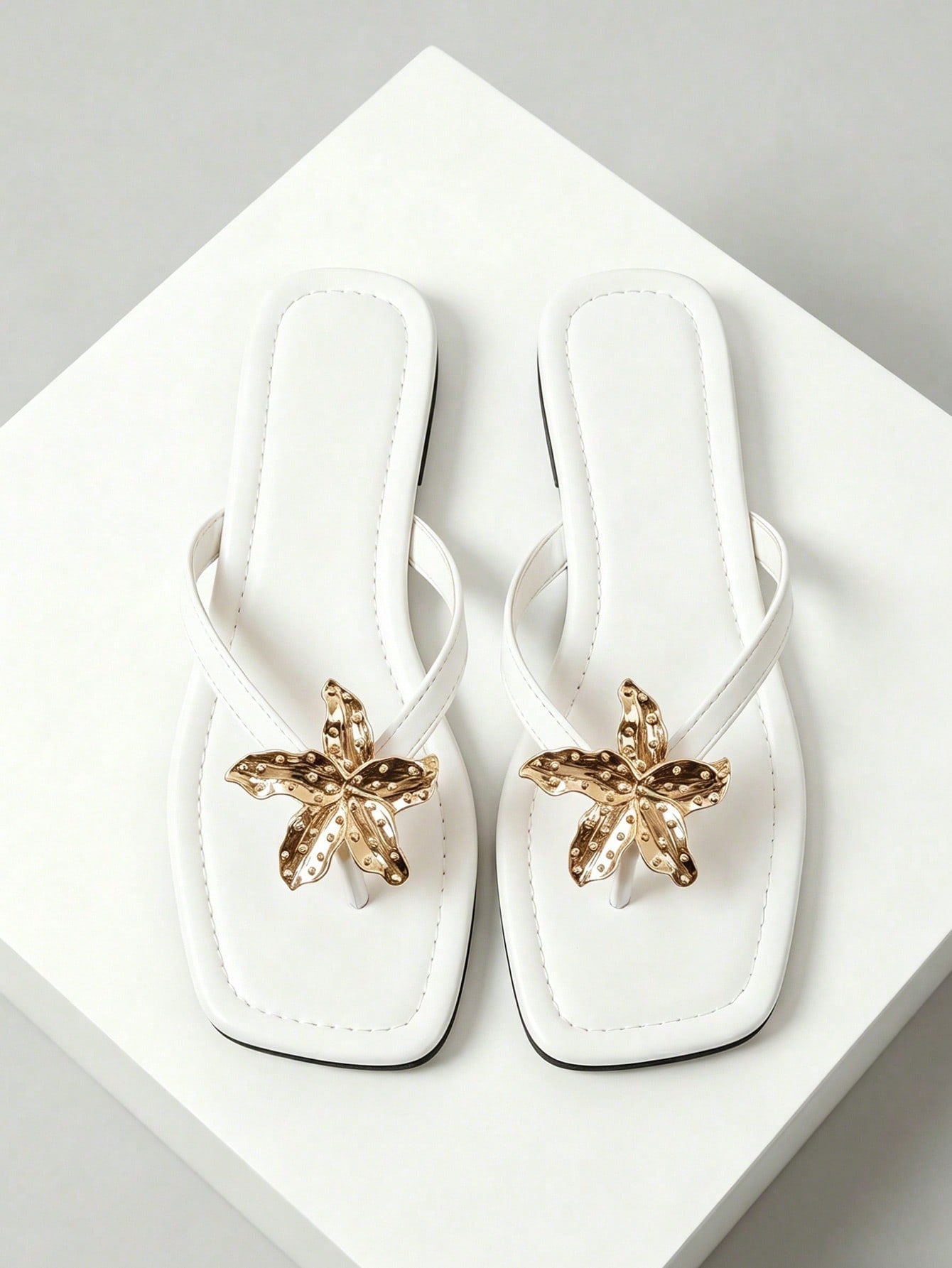 Women's black flat slide sandals with toe post design, textured PU leather straps, and rhinestone heart decoration.