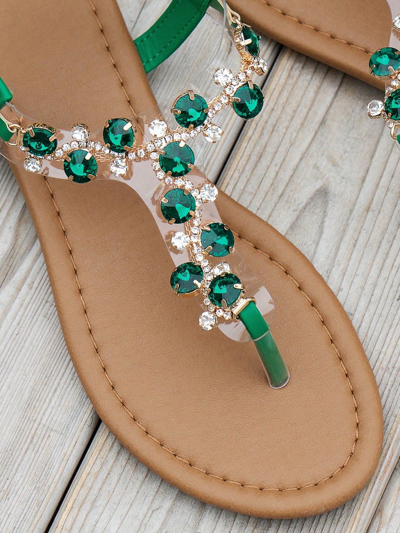 Women's black flat thong sandals with floral print, toe post design, buckle detail, and rhinestone embellishment