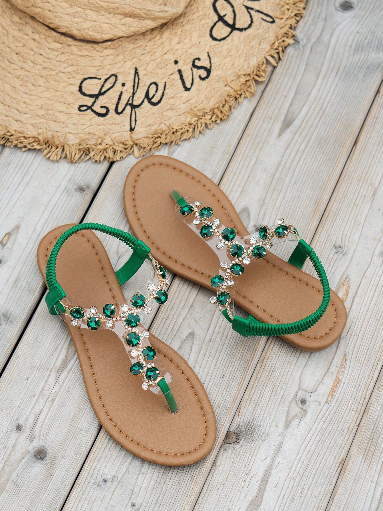 Women's black flat thong sandals with floral print, toe post design, buckle detail, and rhinestone embellishment