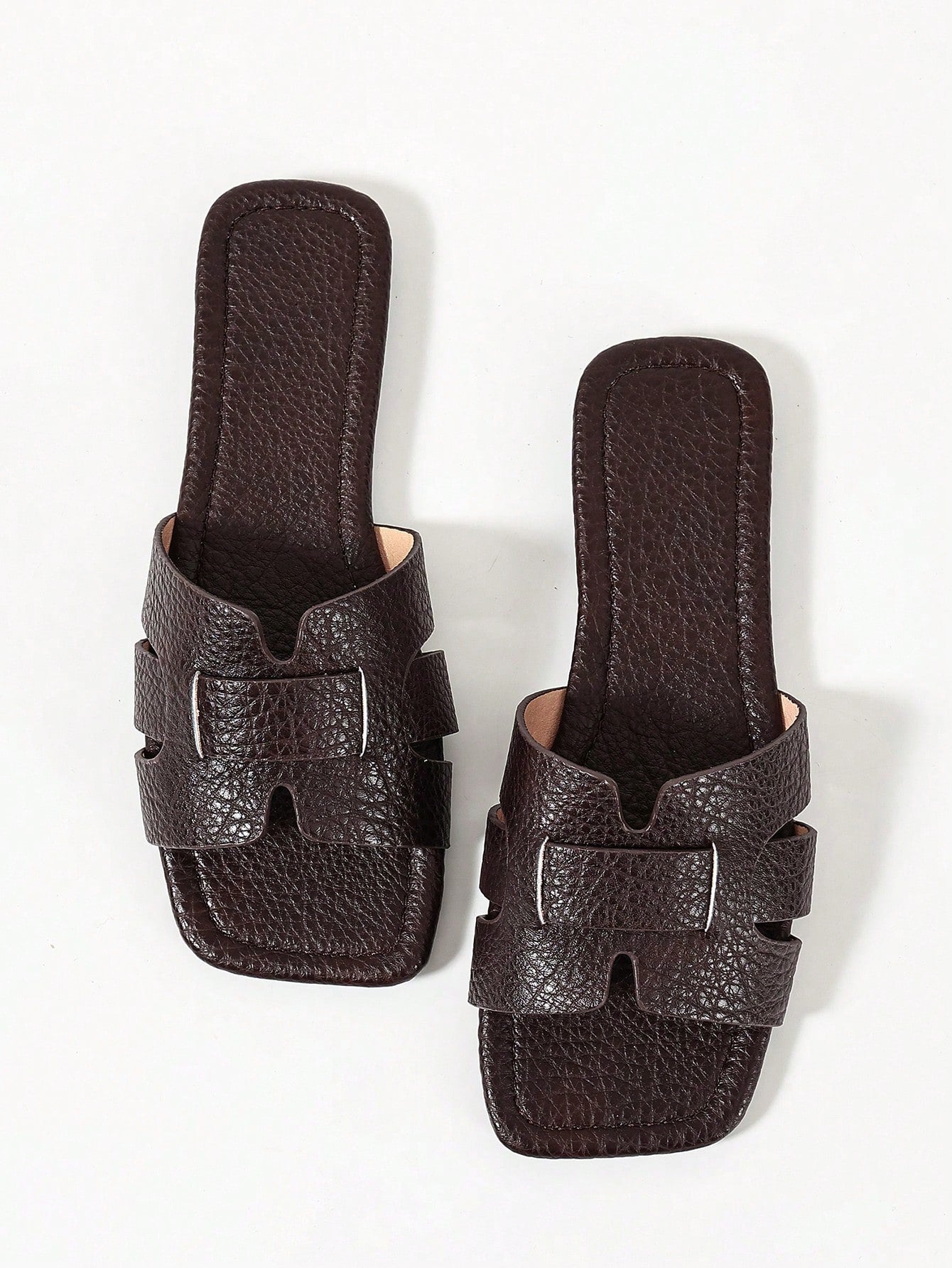 Pair of women’s open-toe flat slide sandals with an H-shaped strap, braided and embossed details, and a minimalist slip-on design suitable for casual outdoor wear.