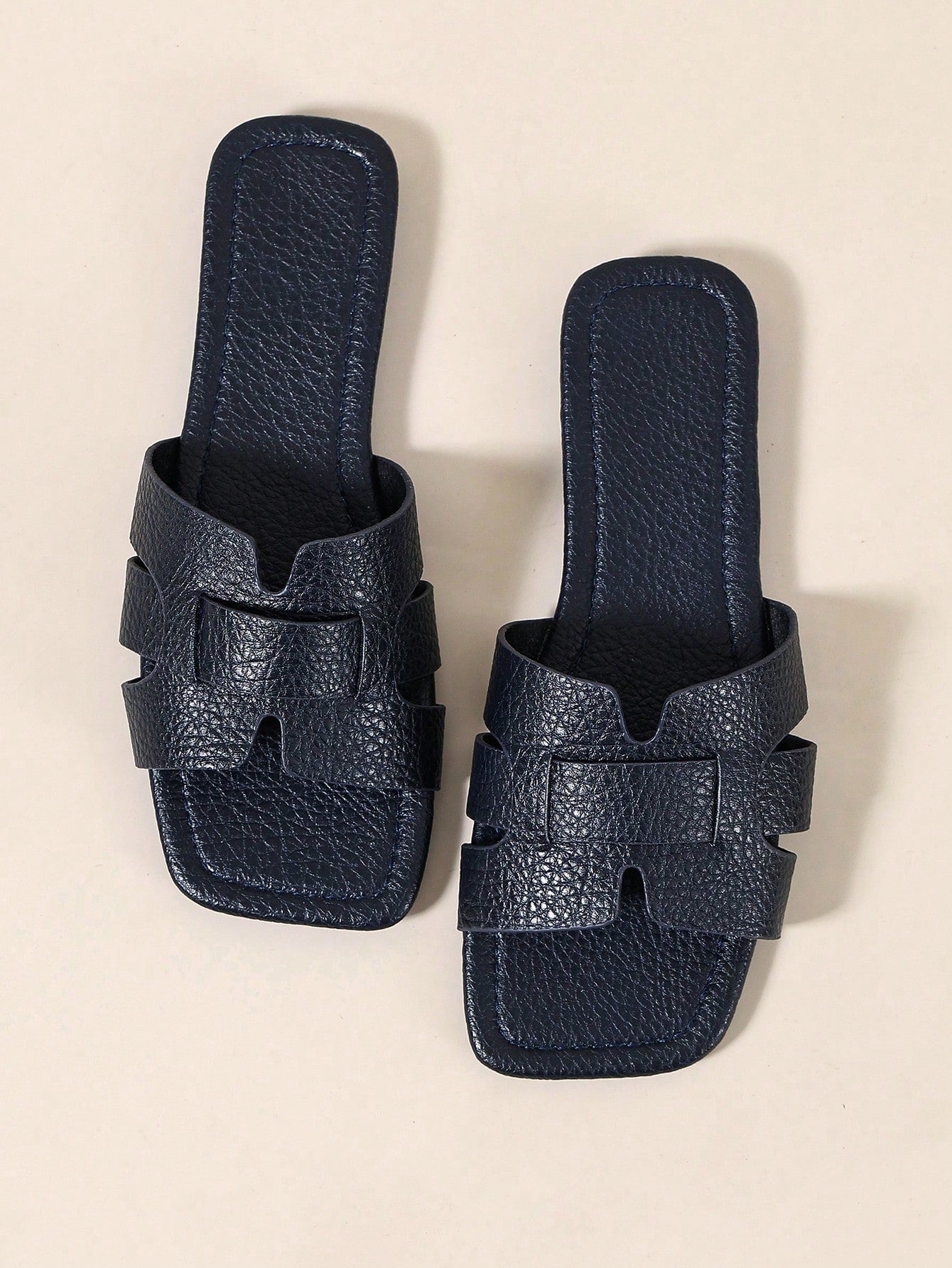 Pair of women’s open-toe flat slide sandals with an H-shaped strap, braided and embossed details, and a minimalist slip-on design suitable for casual outdoor wear.